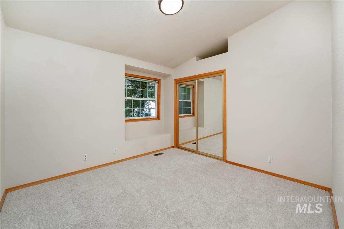 Room featuring light-colored carpeting, white walls, and wood-trim windows