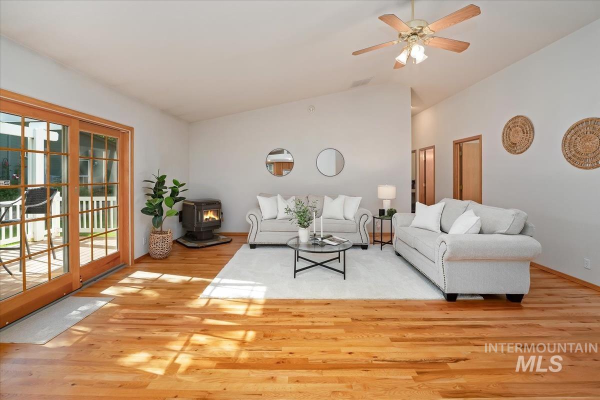 Bright living area featuring wood-finish flooring, a vaulted ceiling, and a wood-burning stove