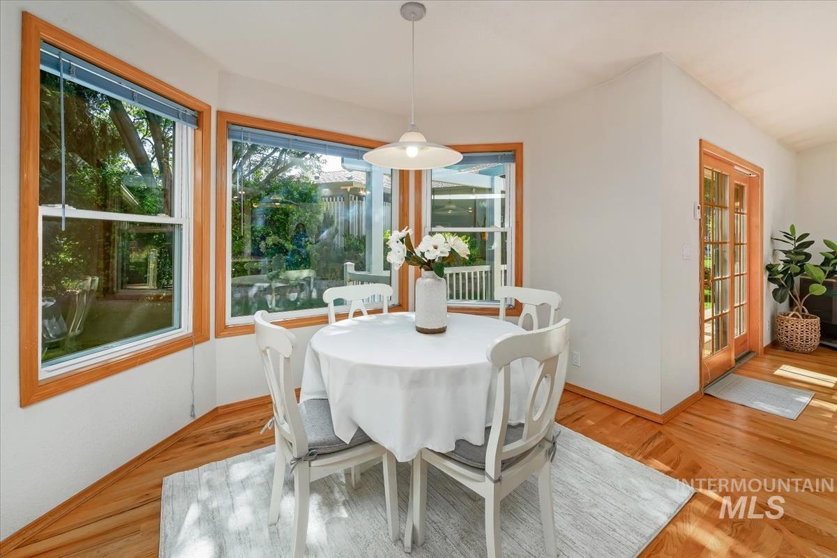 Dining area with hardwood flooring and a bay window featuring three large pane windows with wood-finish trim
