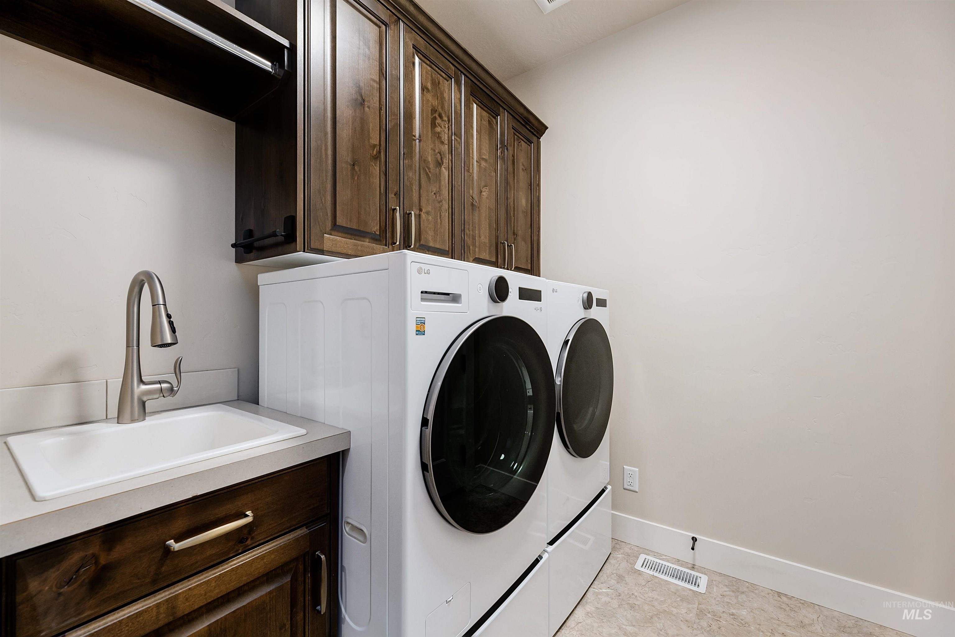 Laundry room with washing machine and clothes dryer, cabinet space, and light tile patterned floors