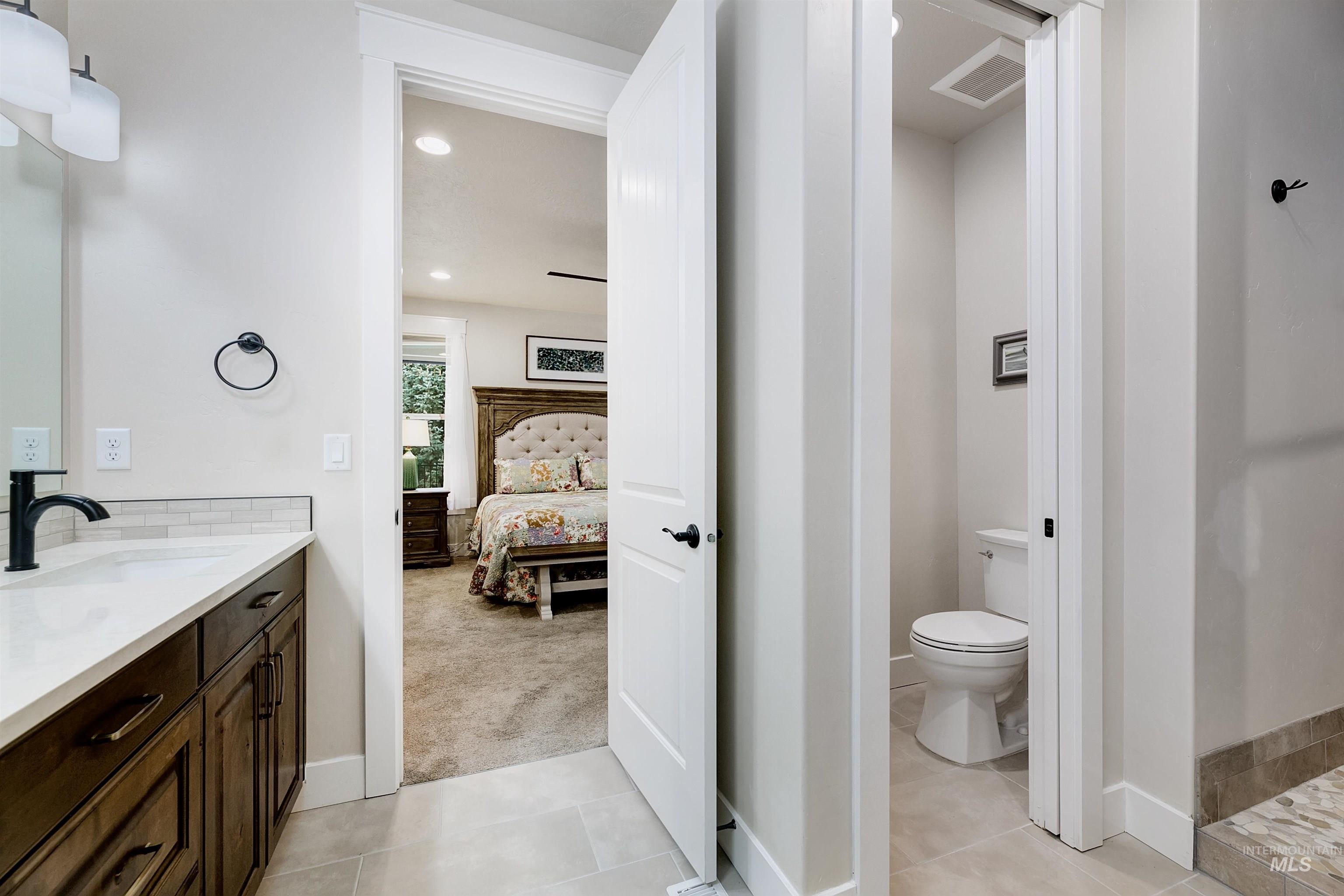 Ensuite bathroom featuring vanity, light carpet, light tile patterned flooring, and recessed lighting