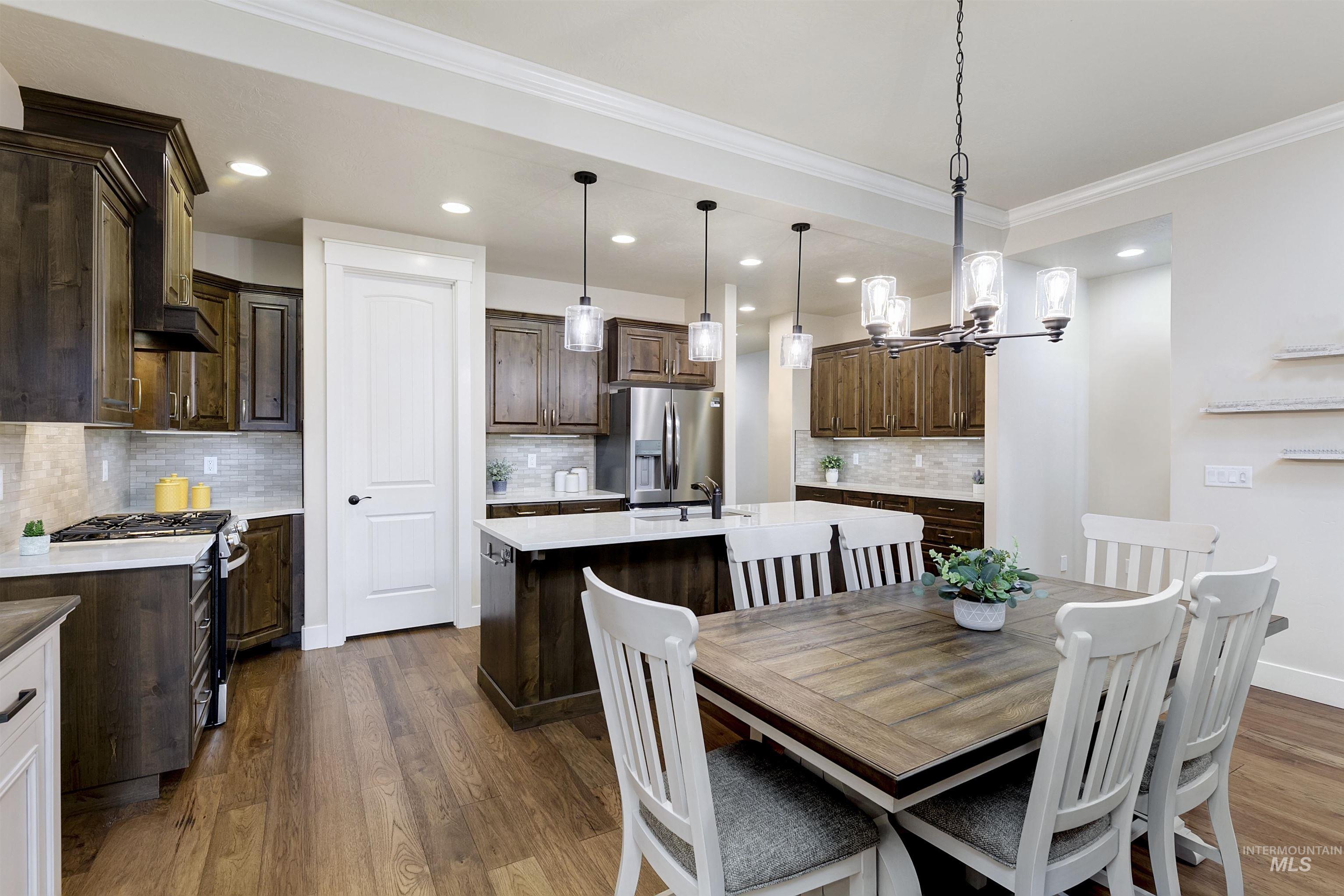 Dining area featuring dark wood finished floors, recessed lighting, ornamental molding, and a chandelier