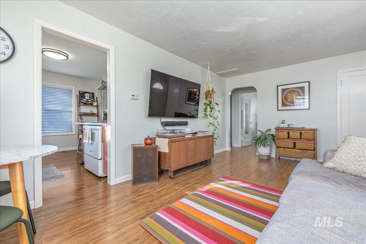 Living room with wood finished floors, arched walkways, and a textured ceiling
