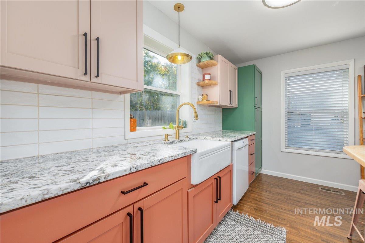 Kitchen with decorative backsplash, dark wood finished floors, healthy amount of natural light, and light stone countertops