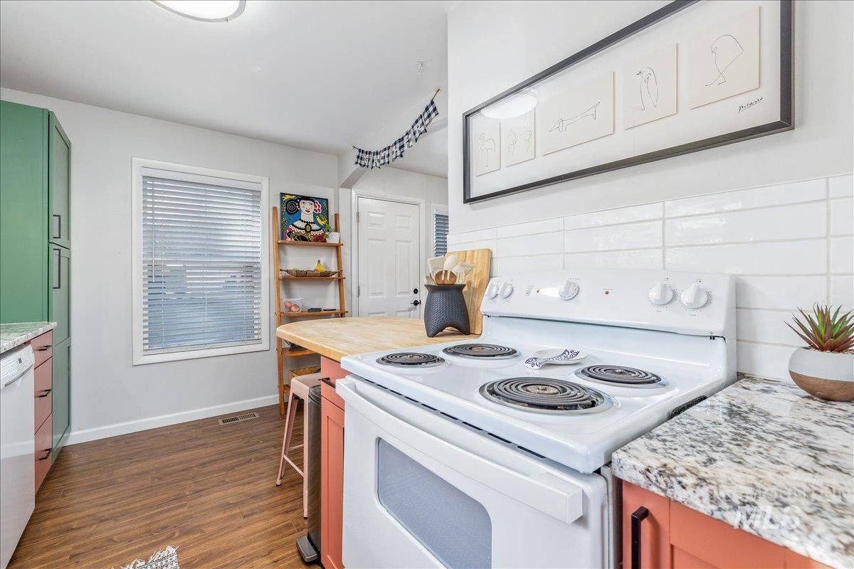 Kitchen featuring white appliances, dark wood-style flooring, tasteful backsplash, and light stone countertops