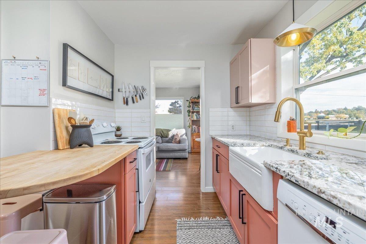 Kitchen featuring white appliances, light wood-style floors, backsplash, and a kitchen bar