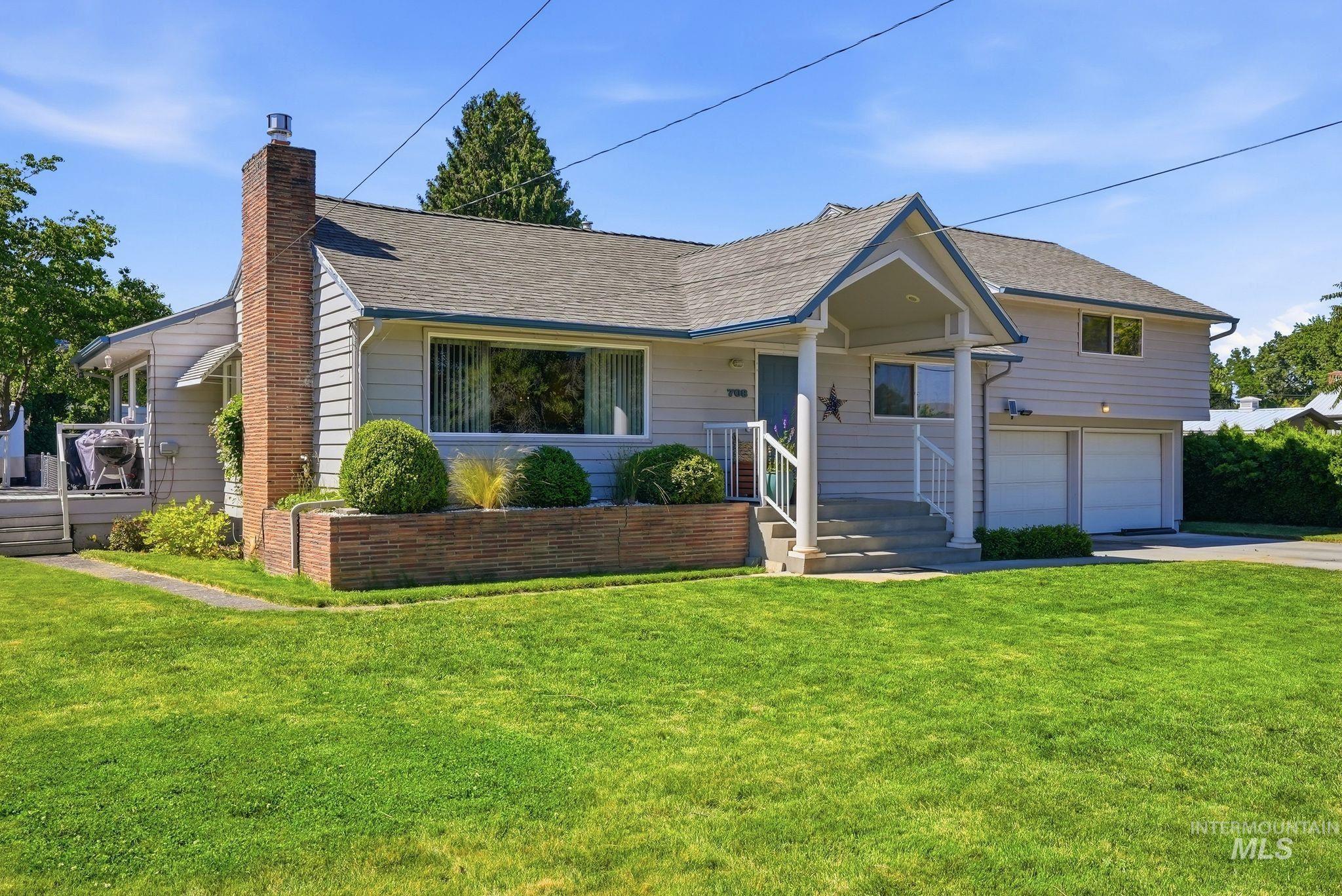Light gray siding exterior with a brick chimney and a covered front porch featuring white columns