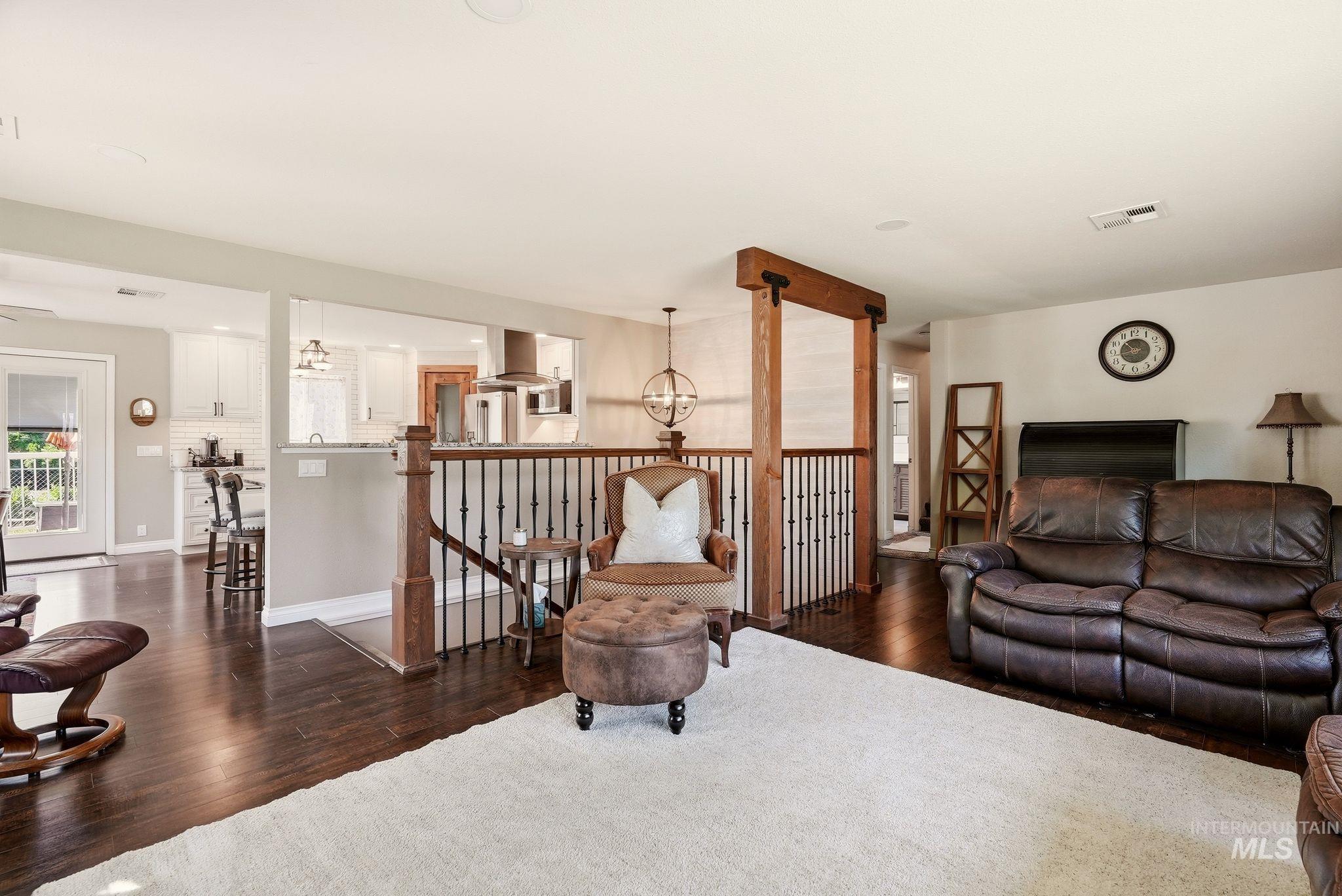 Spacious living area featuring wood-finish flooring, a white area rug, and a rustic wood and metal railing