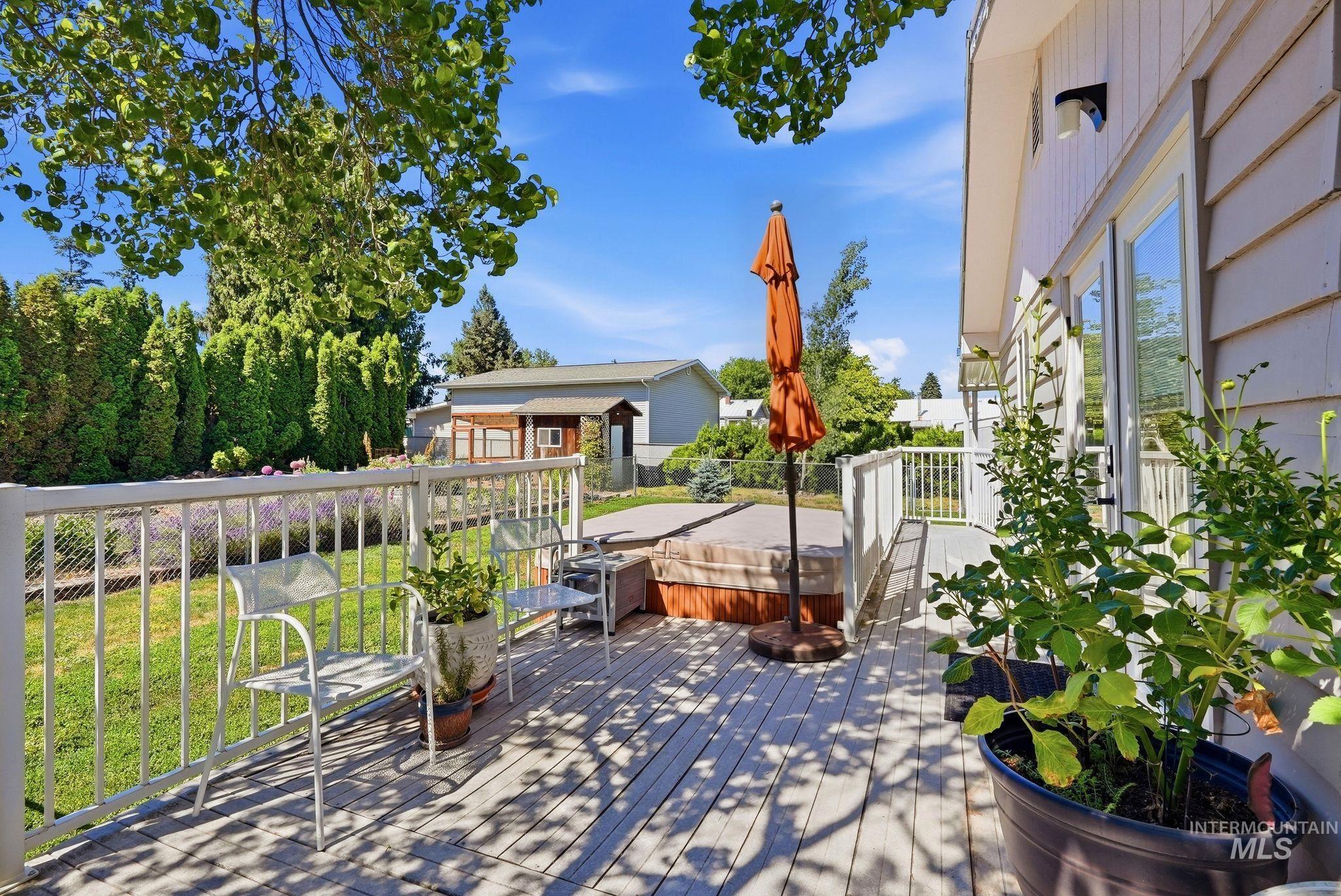 Expansive wood-finish deck featuring a built-in hot tub, white railing, and exterior siding