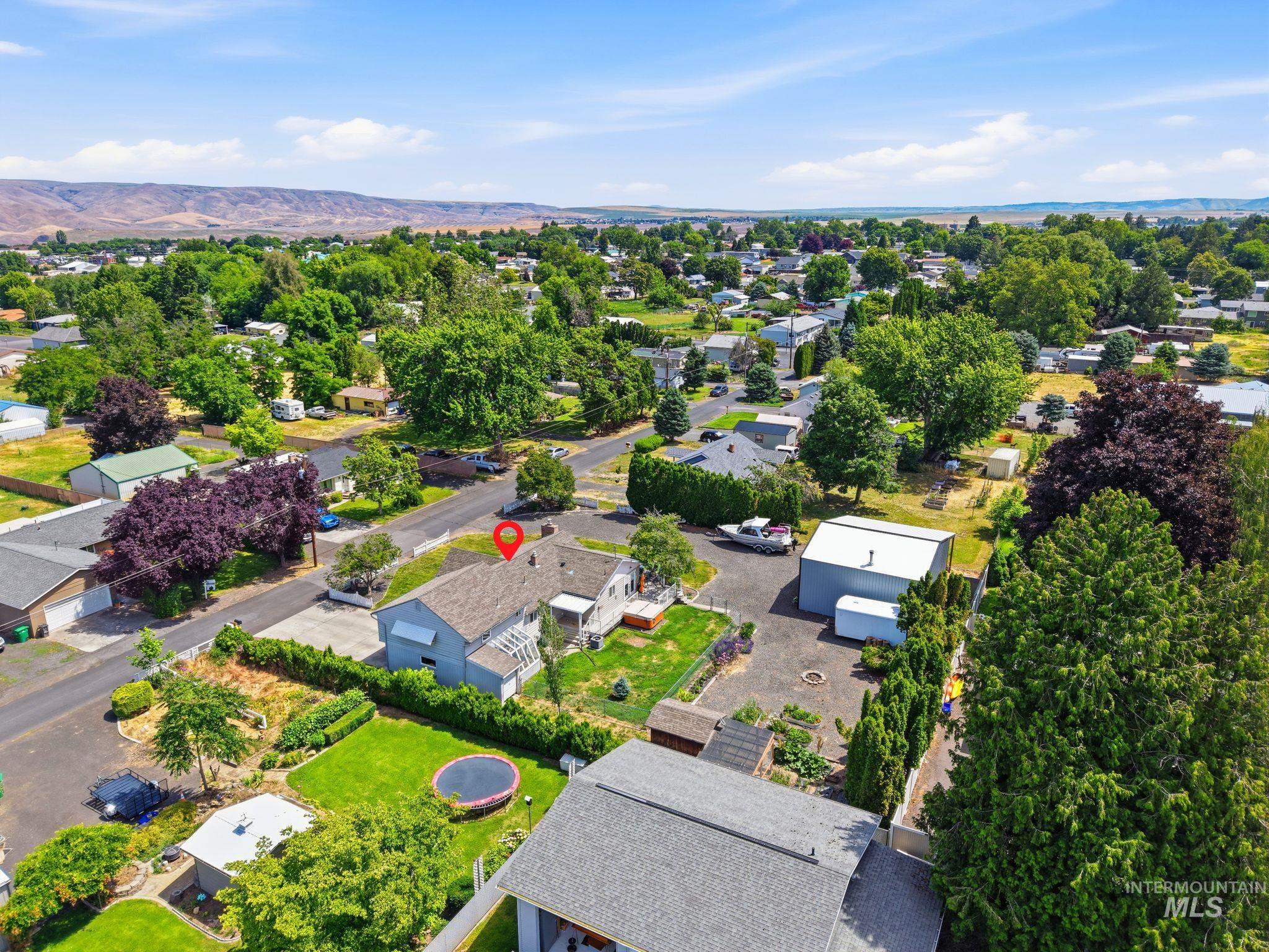 Aerial view showcasing a residential property with a light-colored exterior and a prominent gray roof
