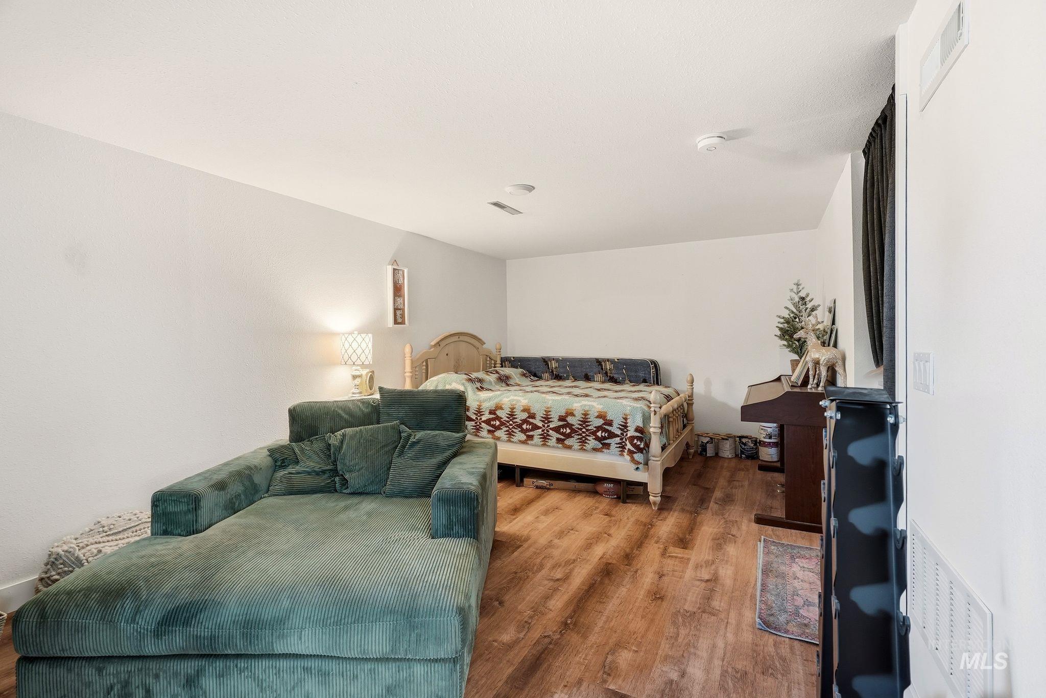 Spacious room featuring wood-finish flooring, white walls, and a ceiling fan