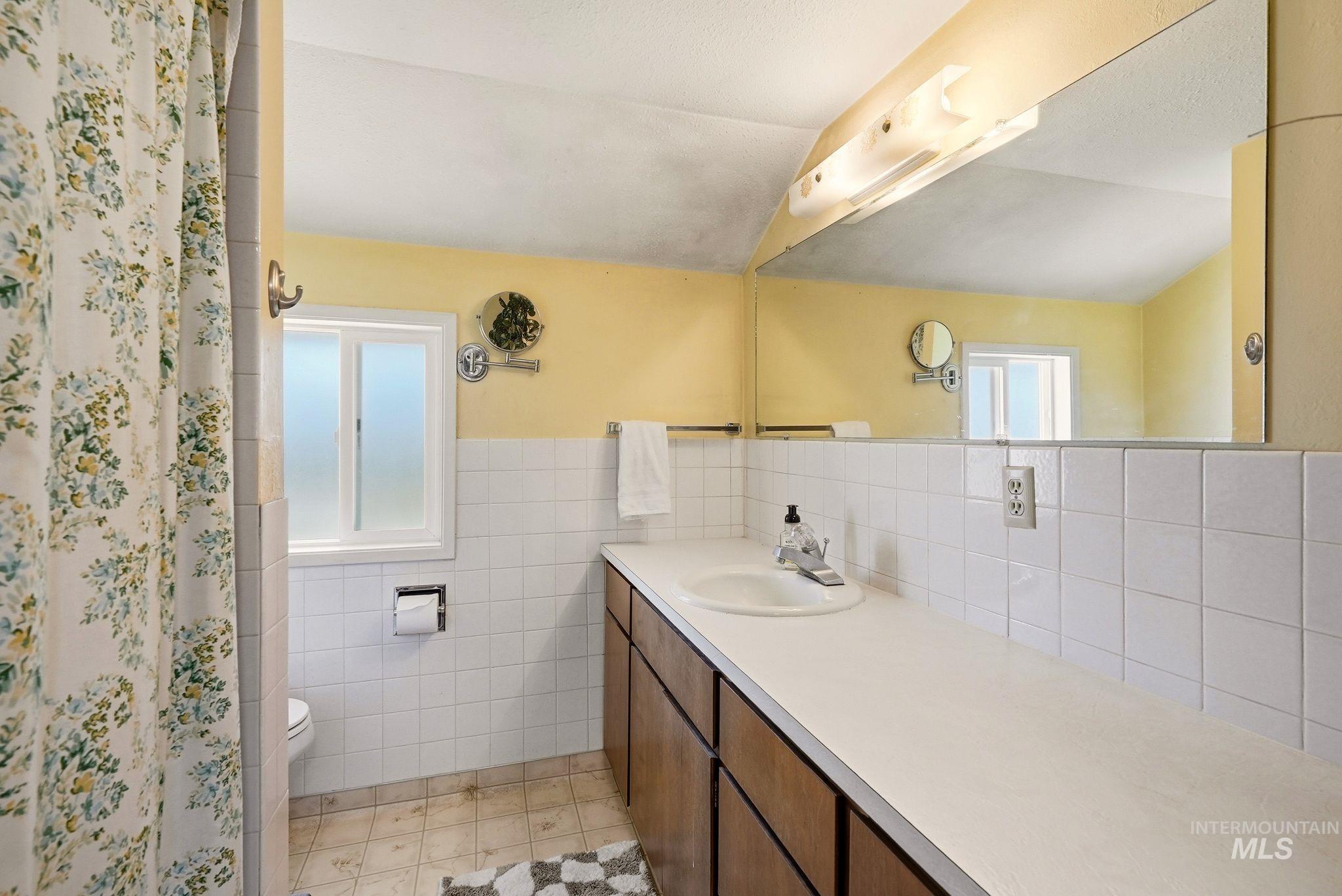 Bathroom featuring a spacious vanity with a white countertop, an integrated sink, and wood-finish cabinetry