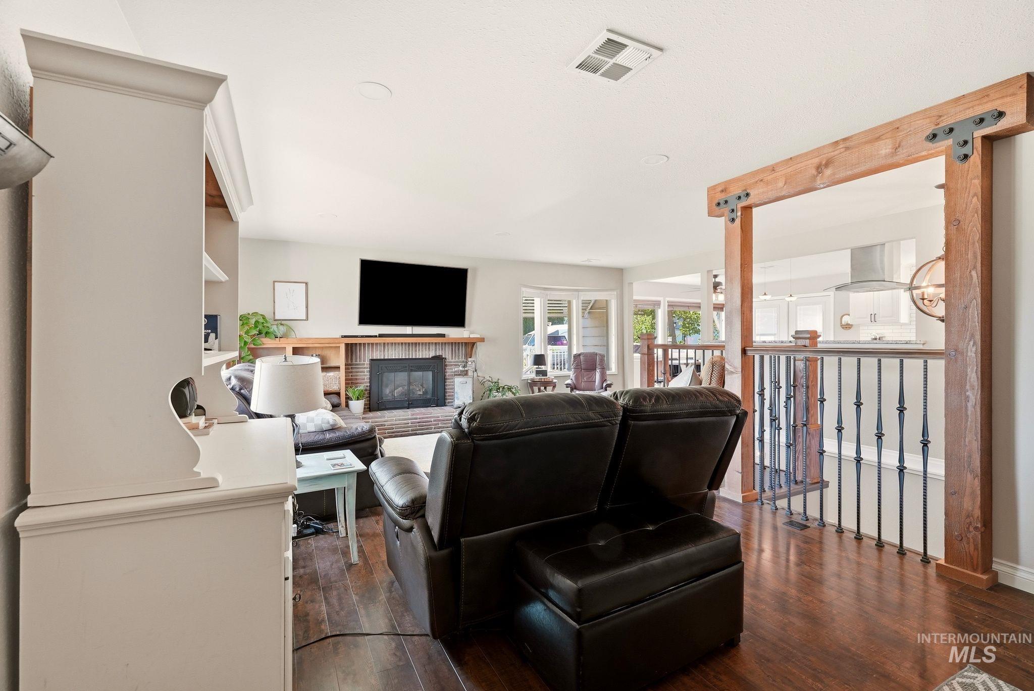 Spacious living area featuring wood-finish flooring, a brick fireplace with a wood mantle, and a built-in entertainment center