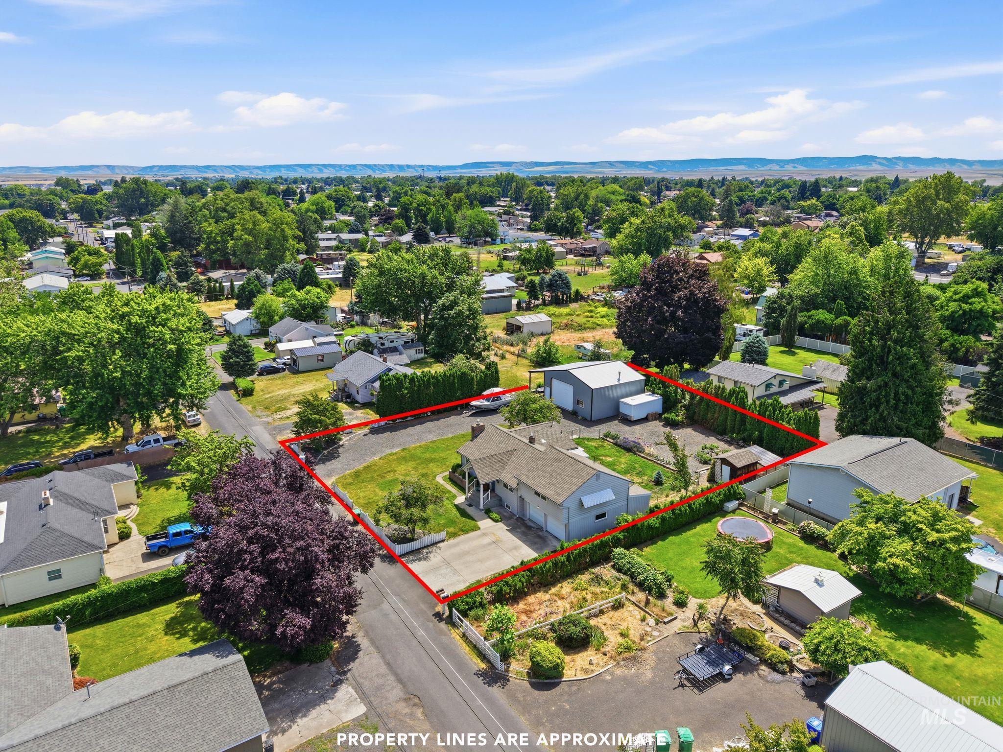 Expansive corner lot featuring a main residence, a detached garage, and mature landscaping