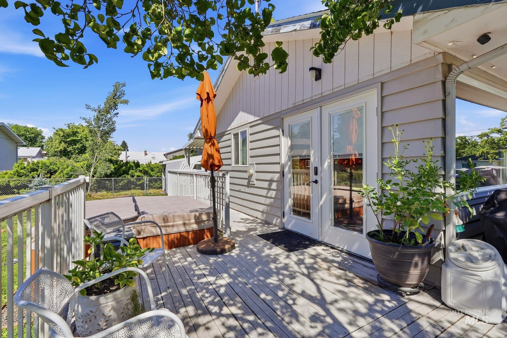 Expansive wooden deck featuring perimeter railing, dual glass-paneled doors, and gray siding exterior