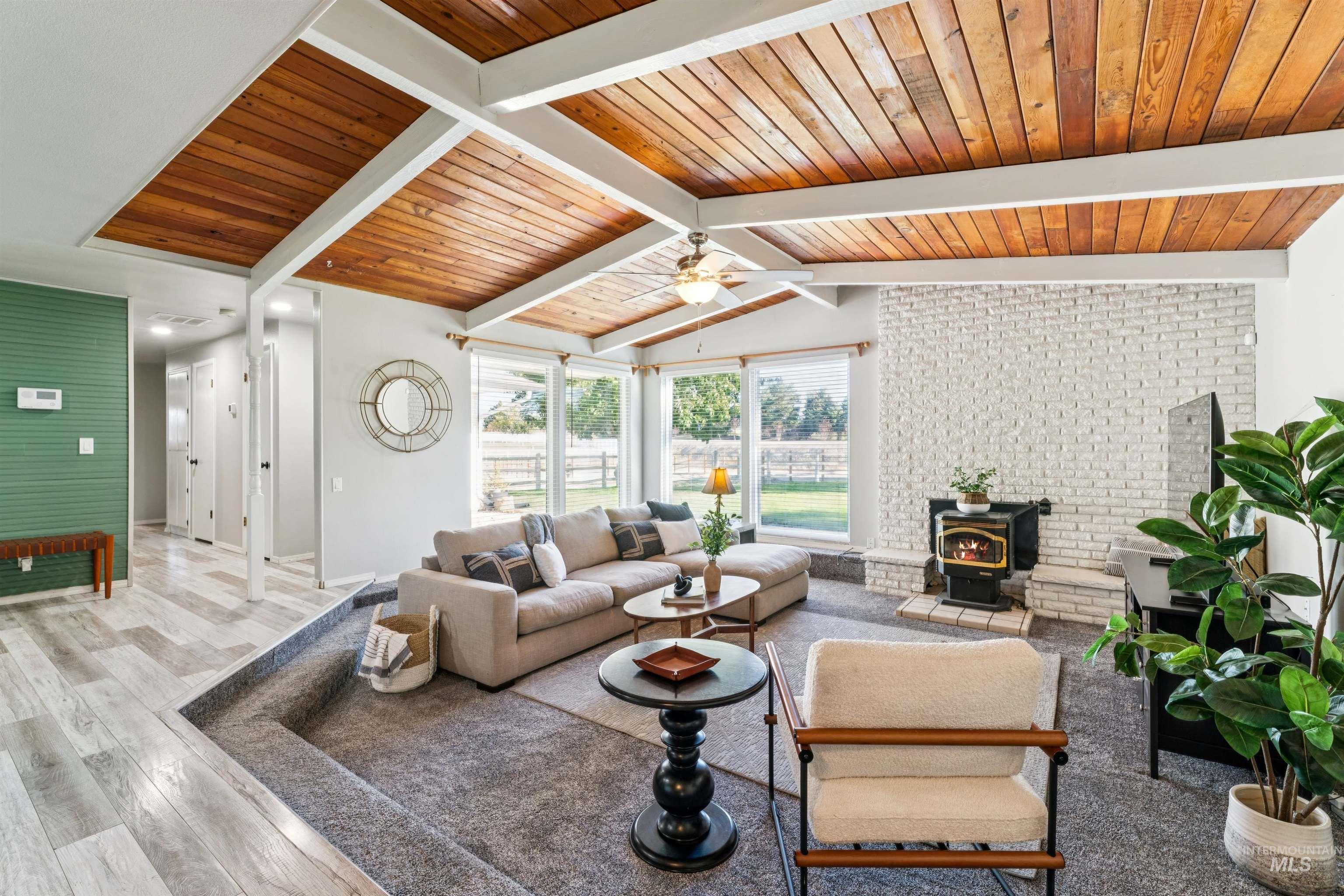 Living room with a wood stove, wood finished floors, and wood ceiling