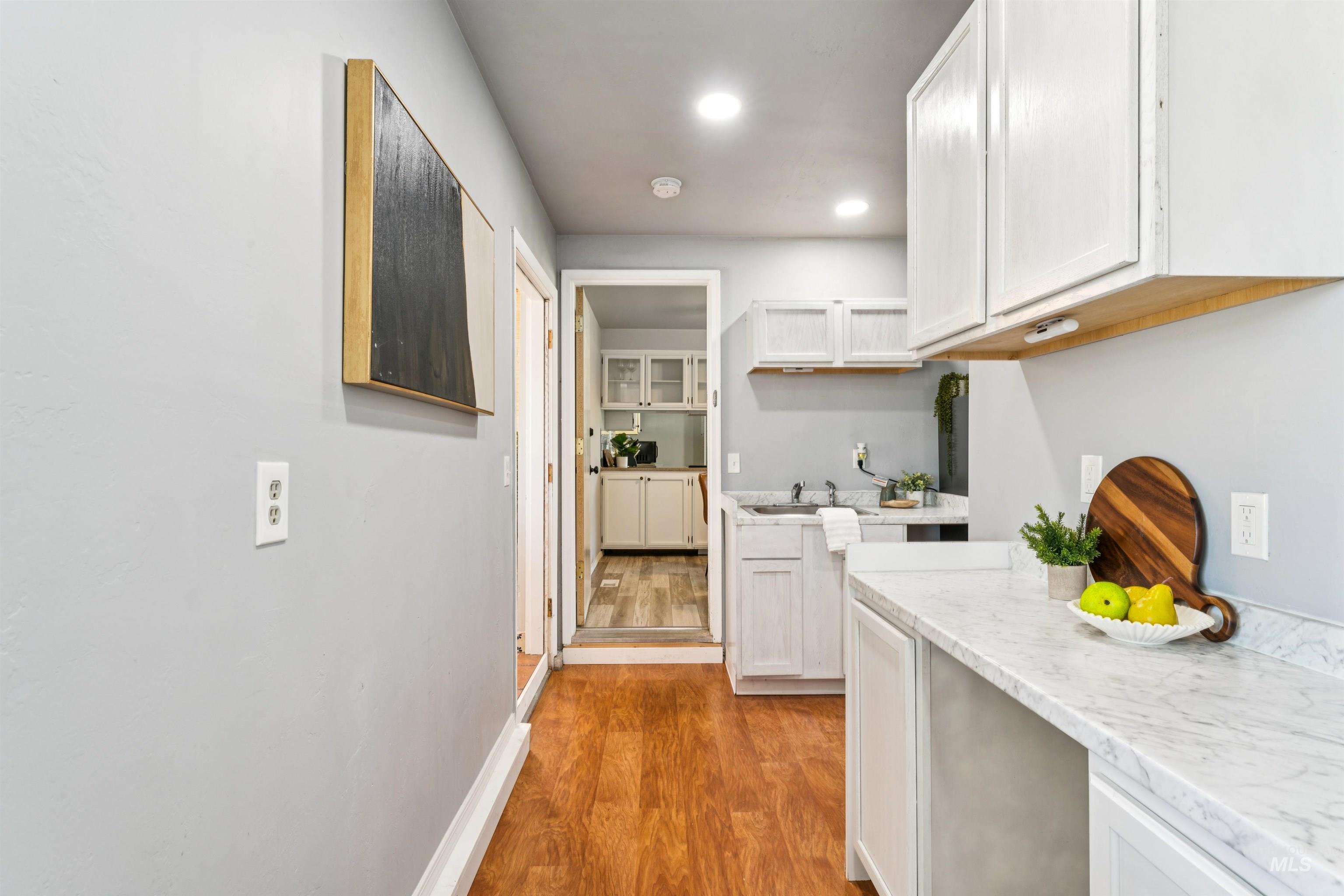 Kitchen featuring light wood-style floors, light stone countertops, white cabinets, and recessed lighting