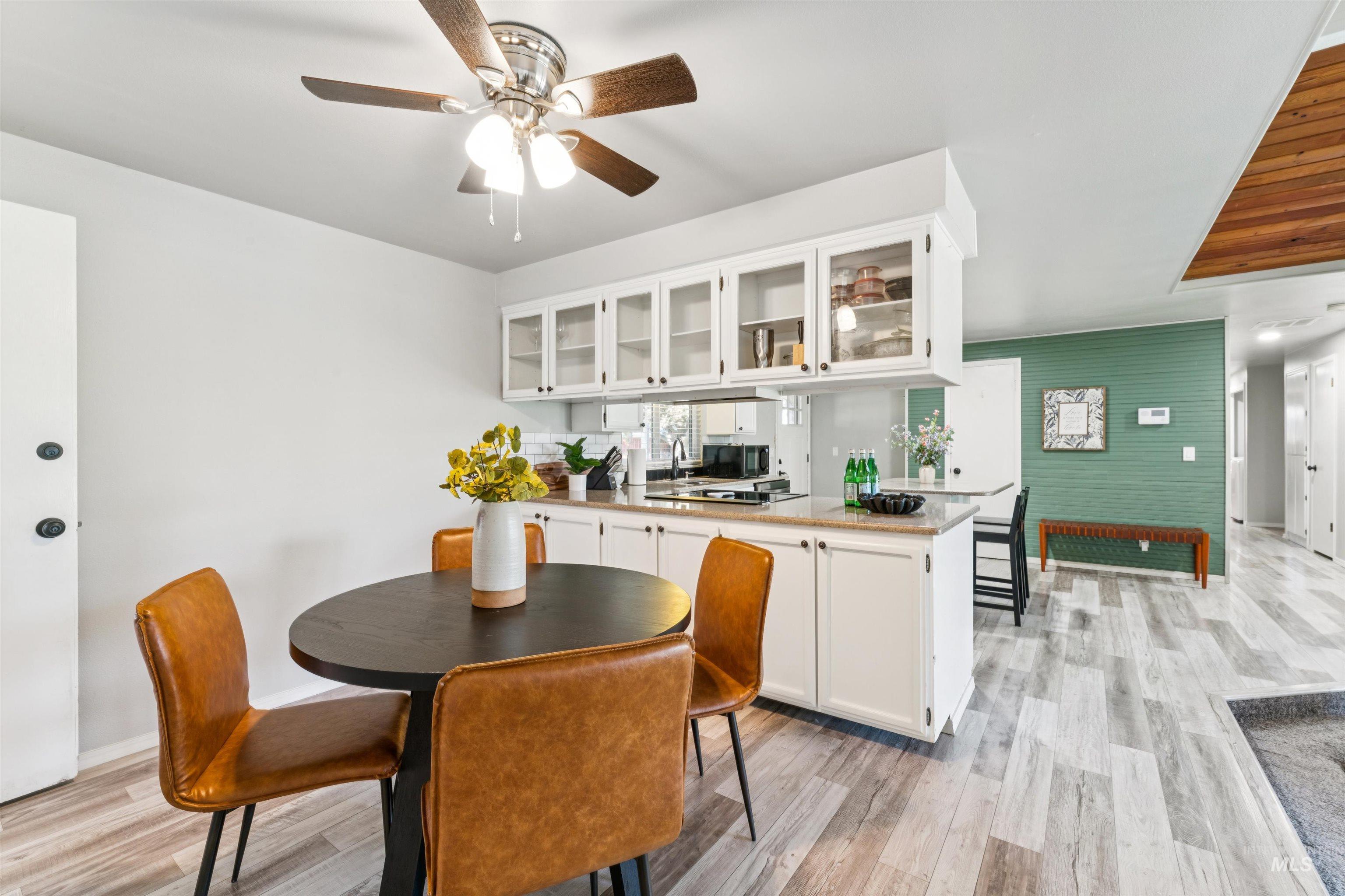Kitchen with white cabinetry, glass insert cabinets, a peninsula, and light wood-type flooring