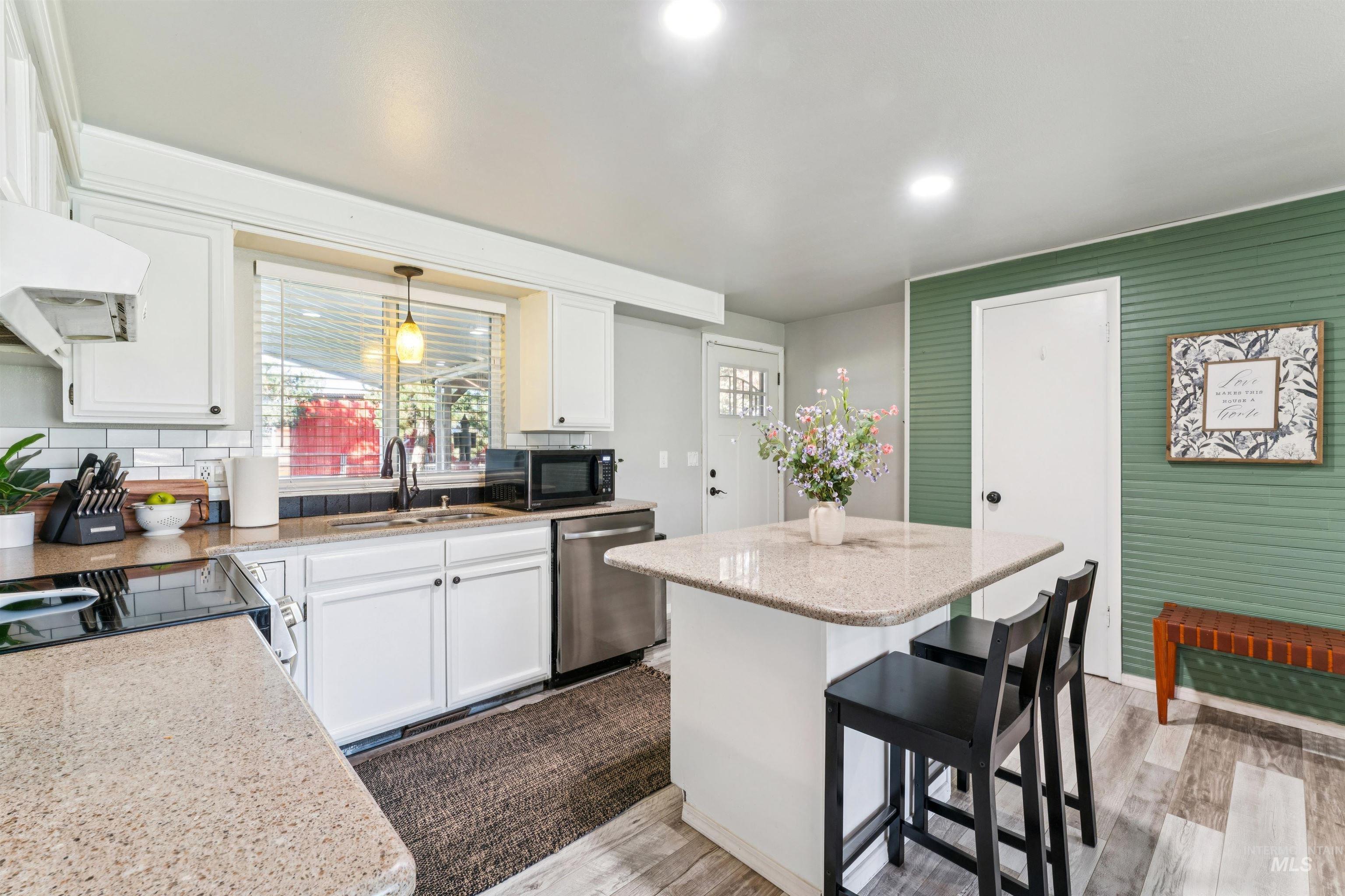 Kitchen featuring white cabinetry, a breakfast bar, a center island, light wood-style flooring, and dishwasher