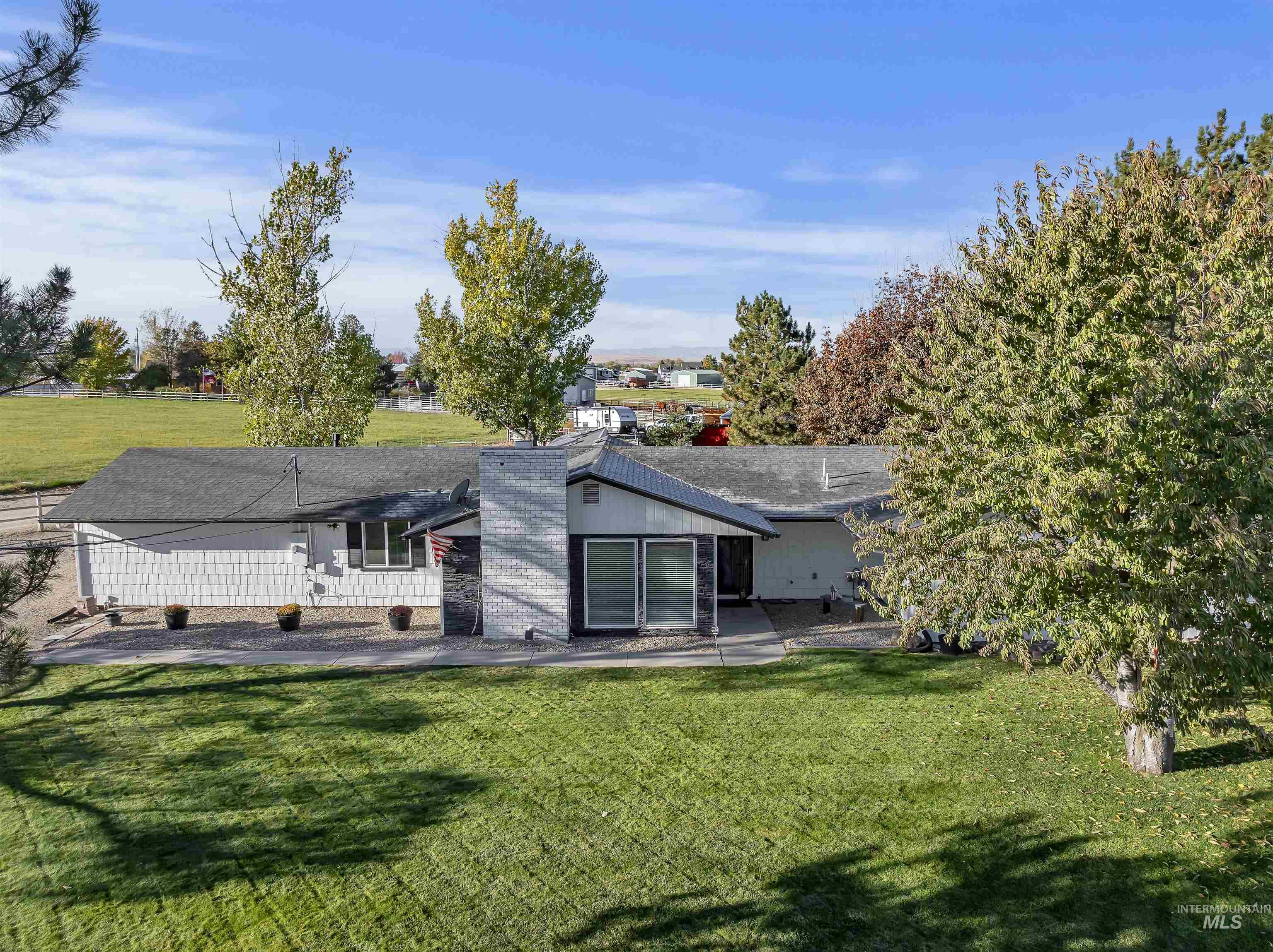 Rear view of property with a lawn, a shingled roof, and a patio area