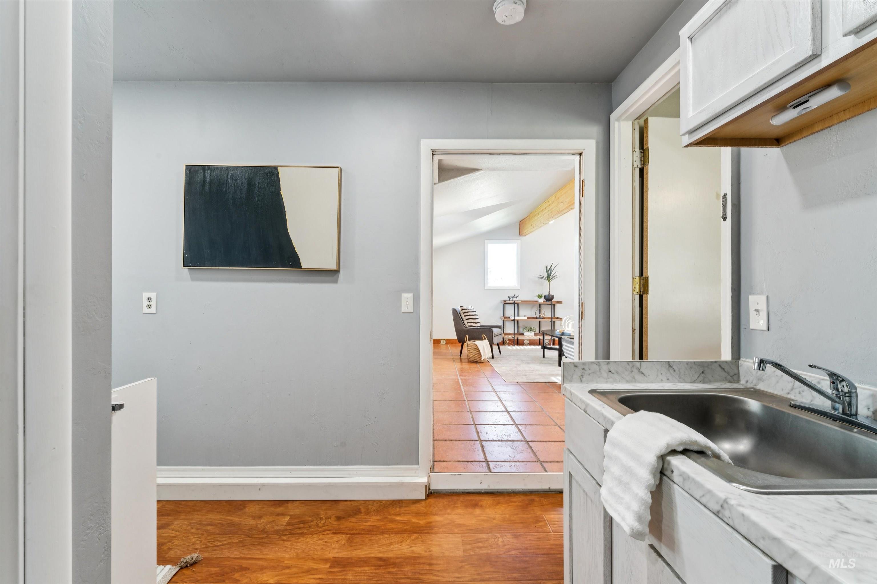 Kitchen featuring light wood-style flooring, white cabinets, and vaulted ceiling