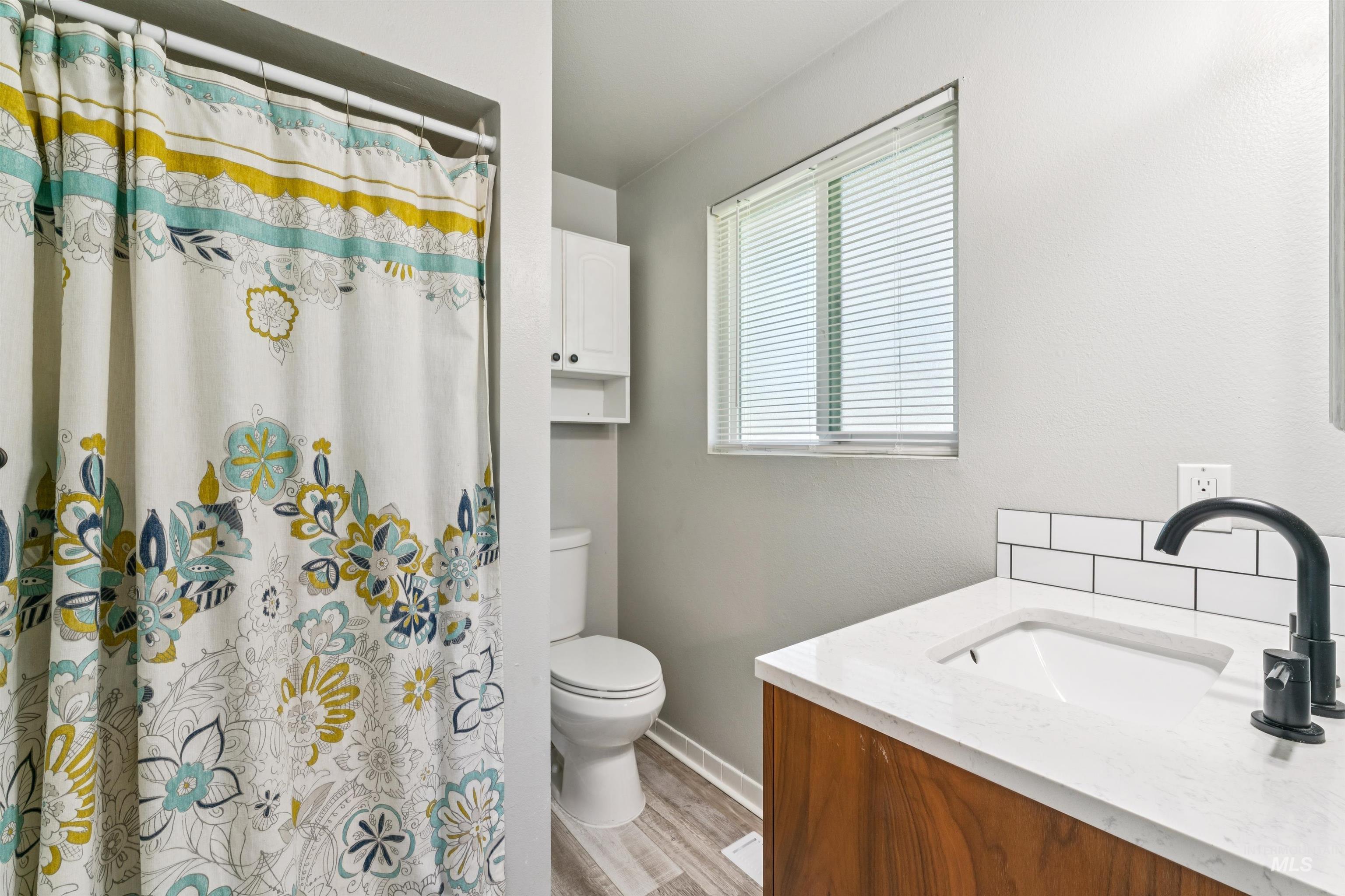 Bathroom featuring vanity, light wood-style floors, and a shower with shower curtain