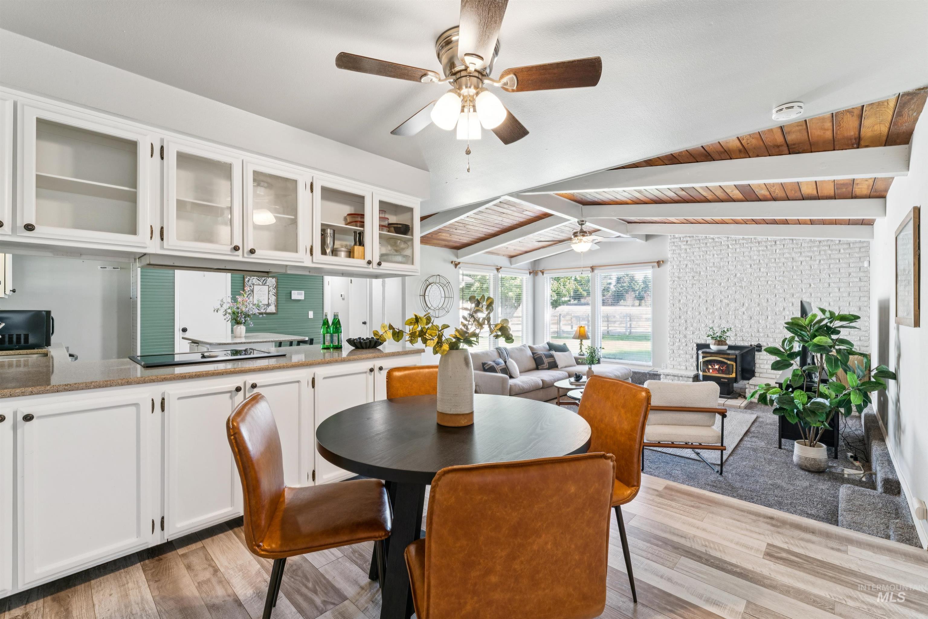 Dining area featuring a wood stove, wood ceiling, light wood-style floors, and ceiling fan