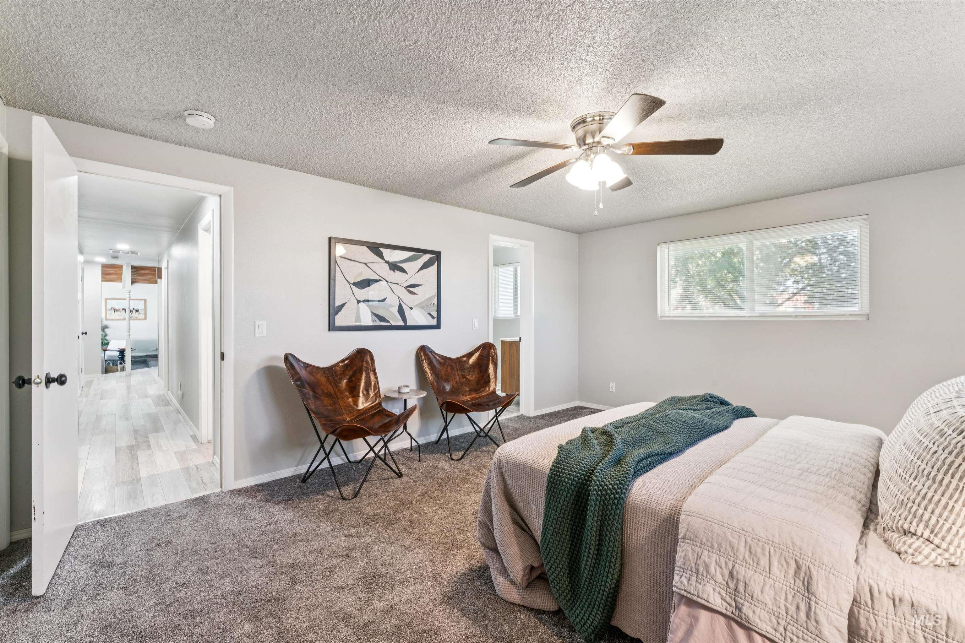 Bedroom featuring carpet flooring, a textured ceiling, a ceiling fan, and ensuite bathroom
