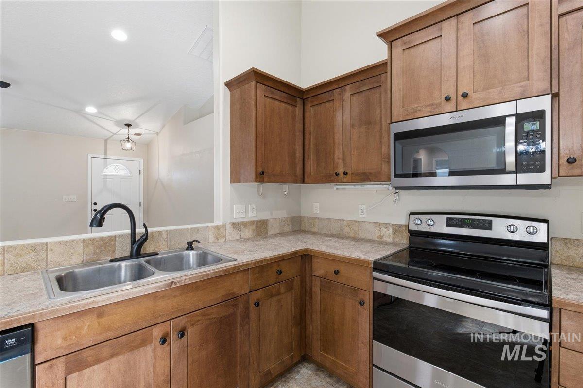 Kitchen featuring stainless steel appliances, light countertops, wood finish cabinetry, and recessed lighting