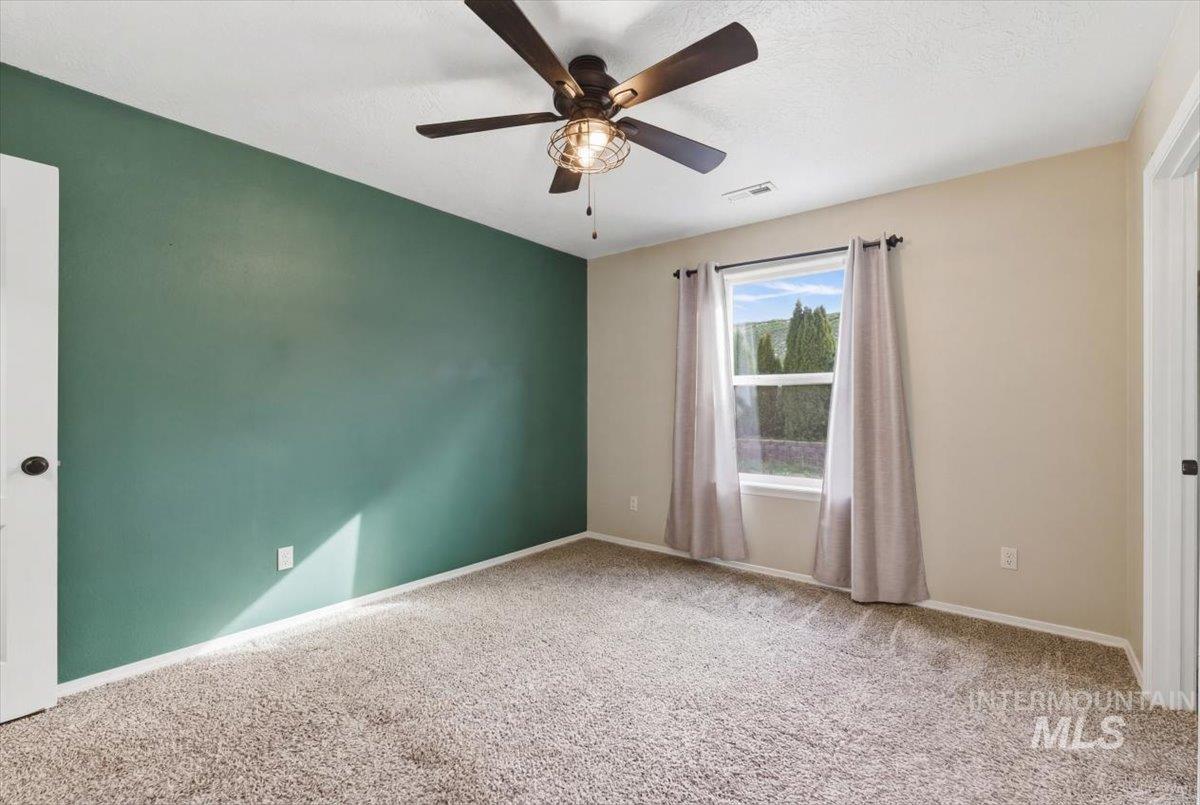 Empty room with ceiling fan and light carpet