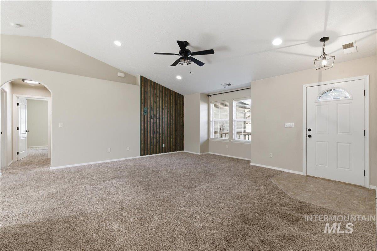 Foyer entrance with vaulted ceiling, arched walkways, light colored carpet, a ceiling fan, and recessed lighting