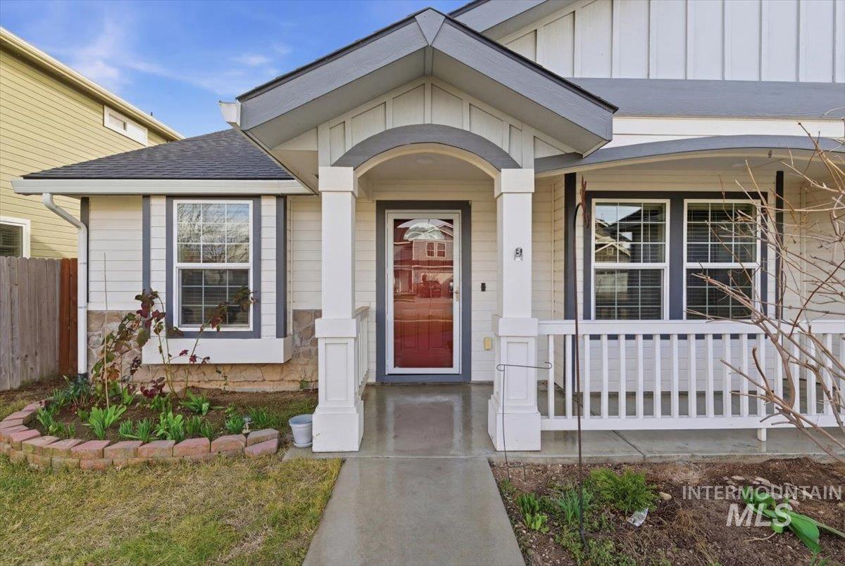Property entrance with board and batten siding, a shingled roof, and covered porch