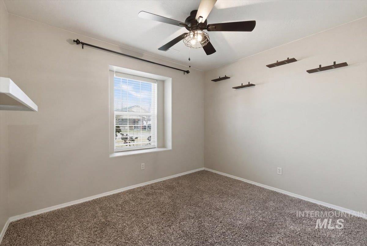 Spare room featuring dark colored carpet and ceiling fan