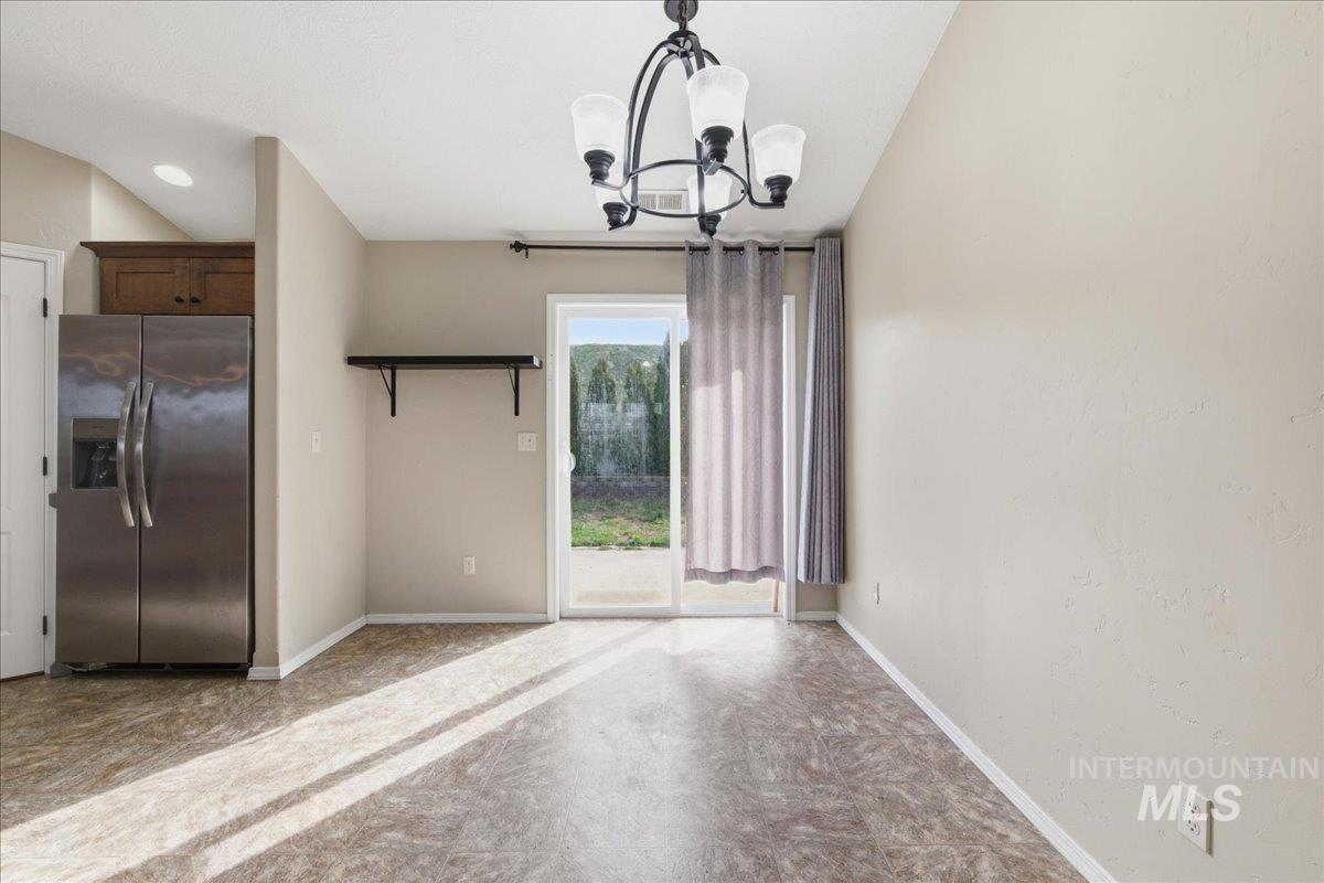 Unfurnished dining area with suspended lighting and baseboards