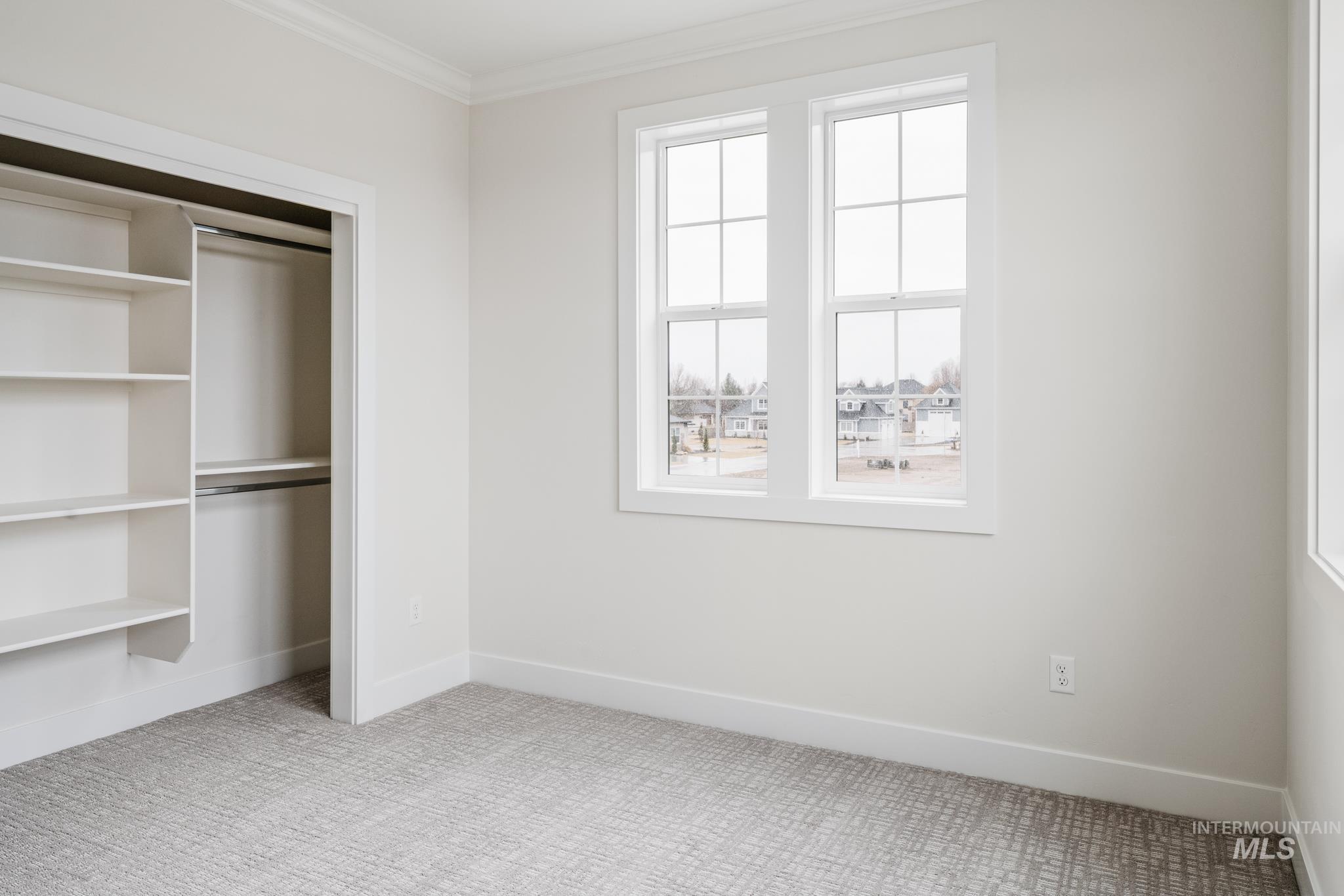 Unfurnished bedroom featuring light colored carpet, a closet, and ornamental molding