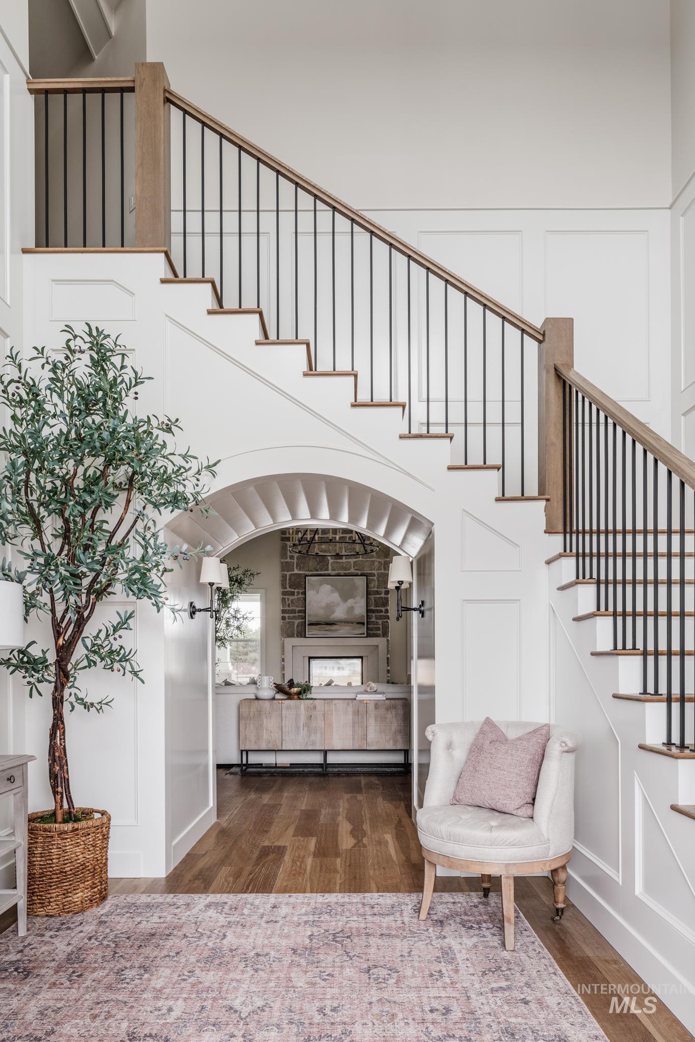 Stairway with a decorative wall, wood finished floors, a multi sided fireplace, and a towering ceiling