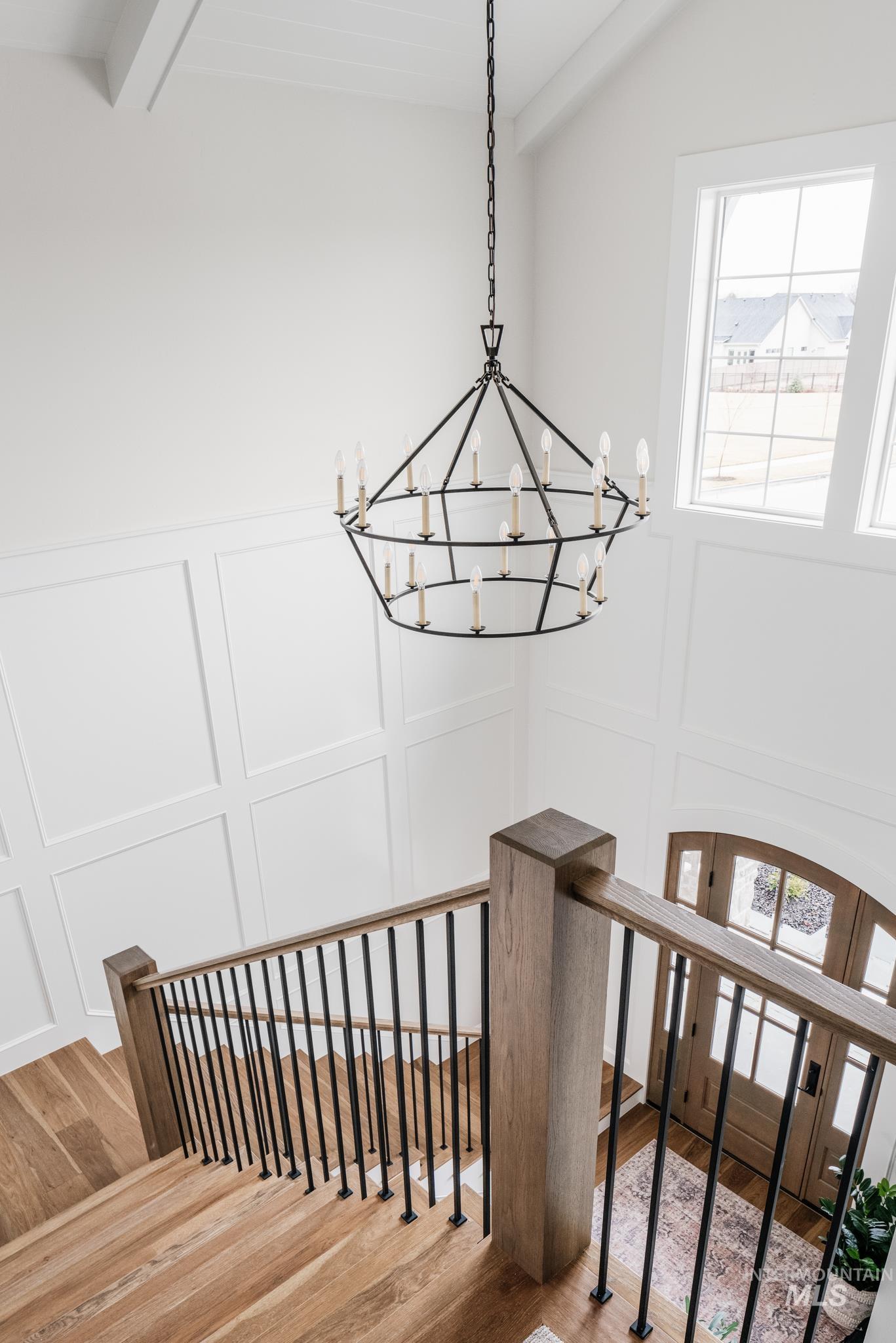 Stairs with wood finished floors, a chandelier, a decorative wall, and beam ceiling