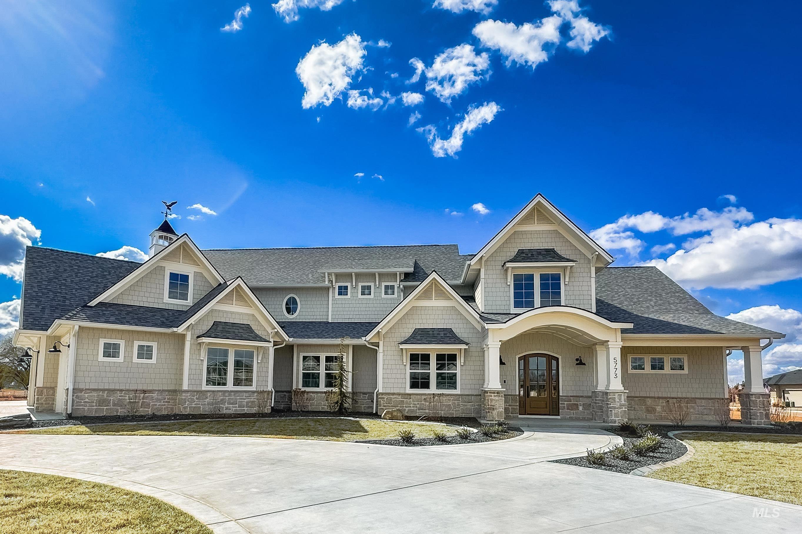 View of front facade with stone siding, a shingled roof, and a porch