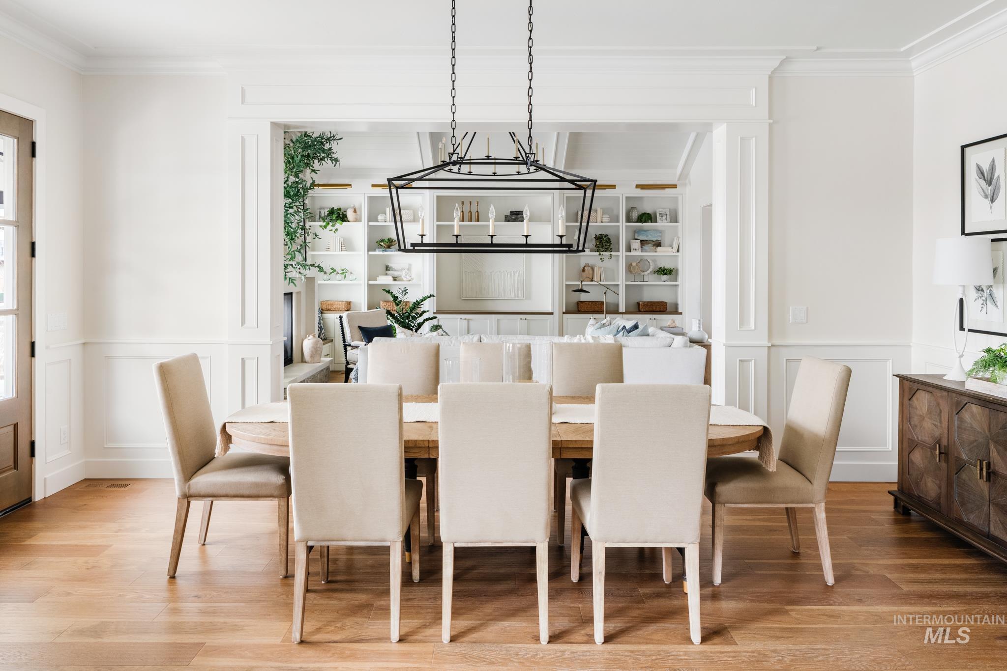 Dining area featuring a decorative wall, a wainscoted wall, ornamental molding, light wood-style flooring, and a chandelier