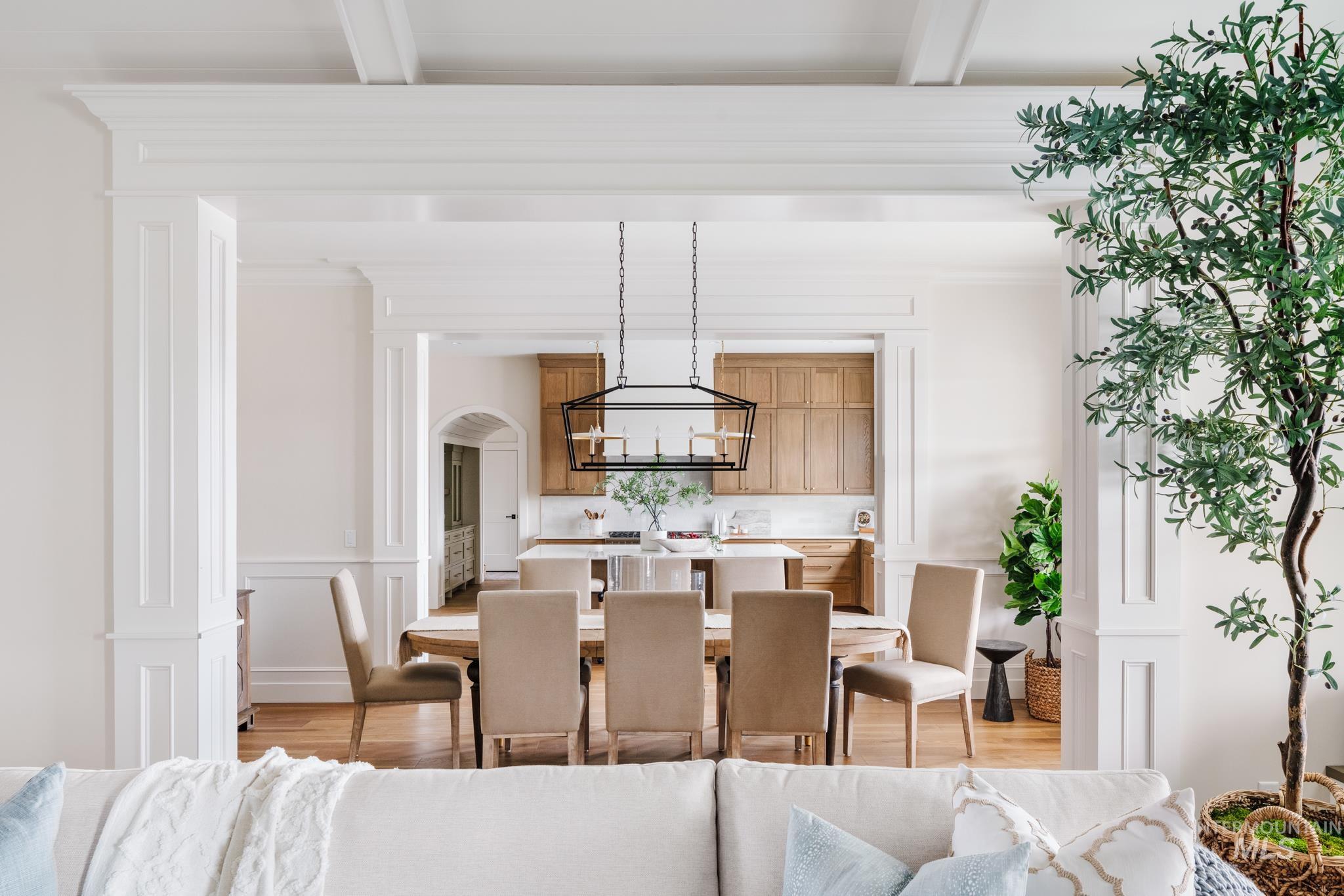 Dining room with light wood-type flooring, arched walkways, crown molding, and a decorative wall