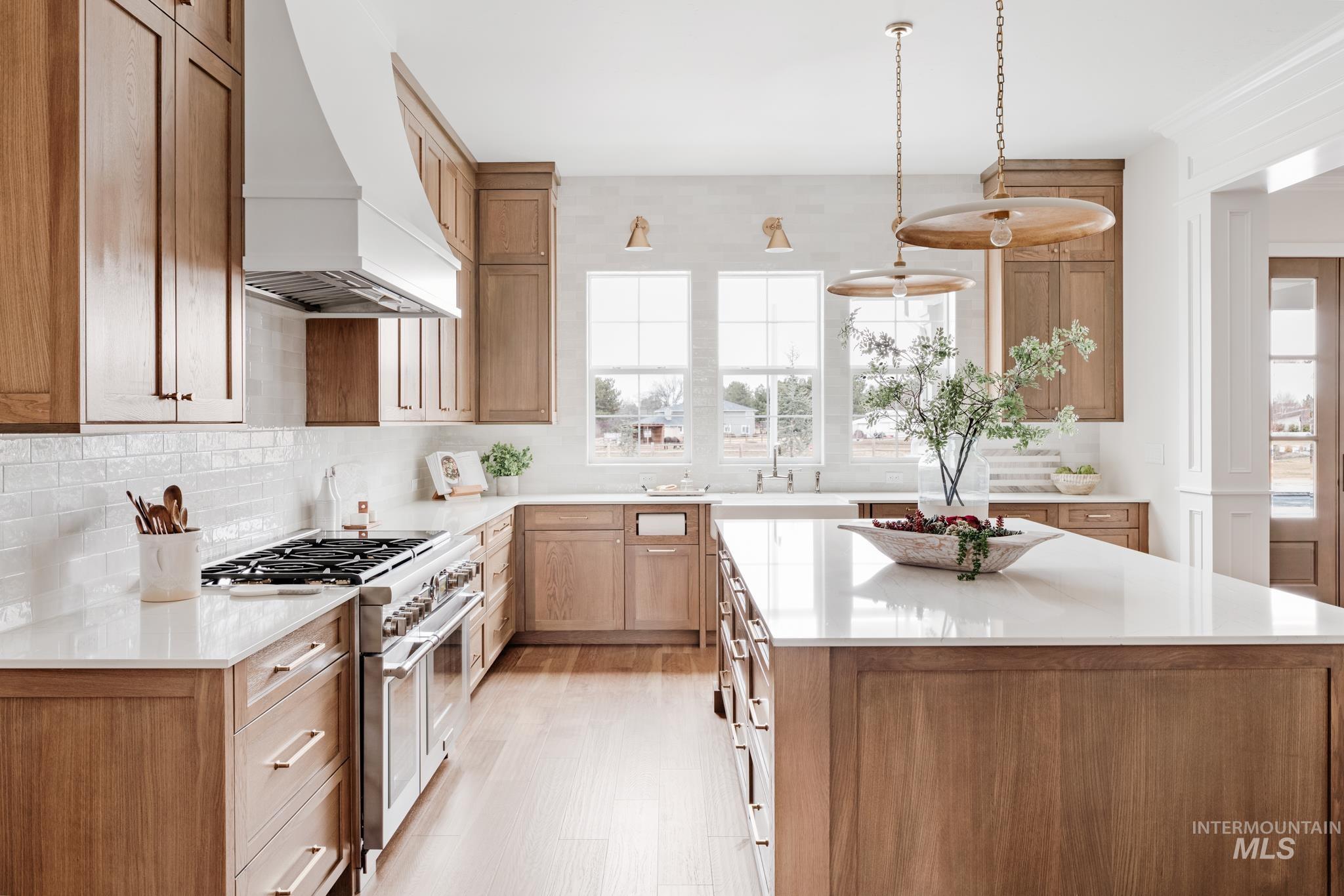 Kitchen featuring custom exhaust hood, double oven range, a center island, and light stone counters