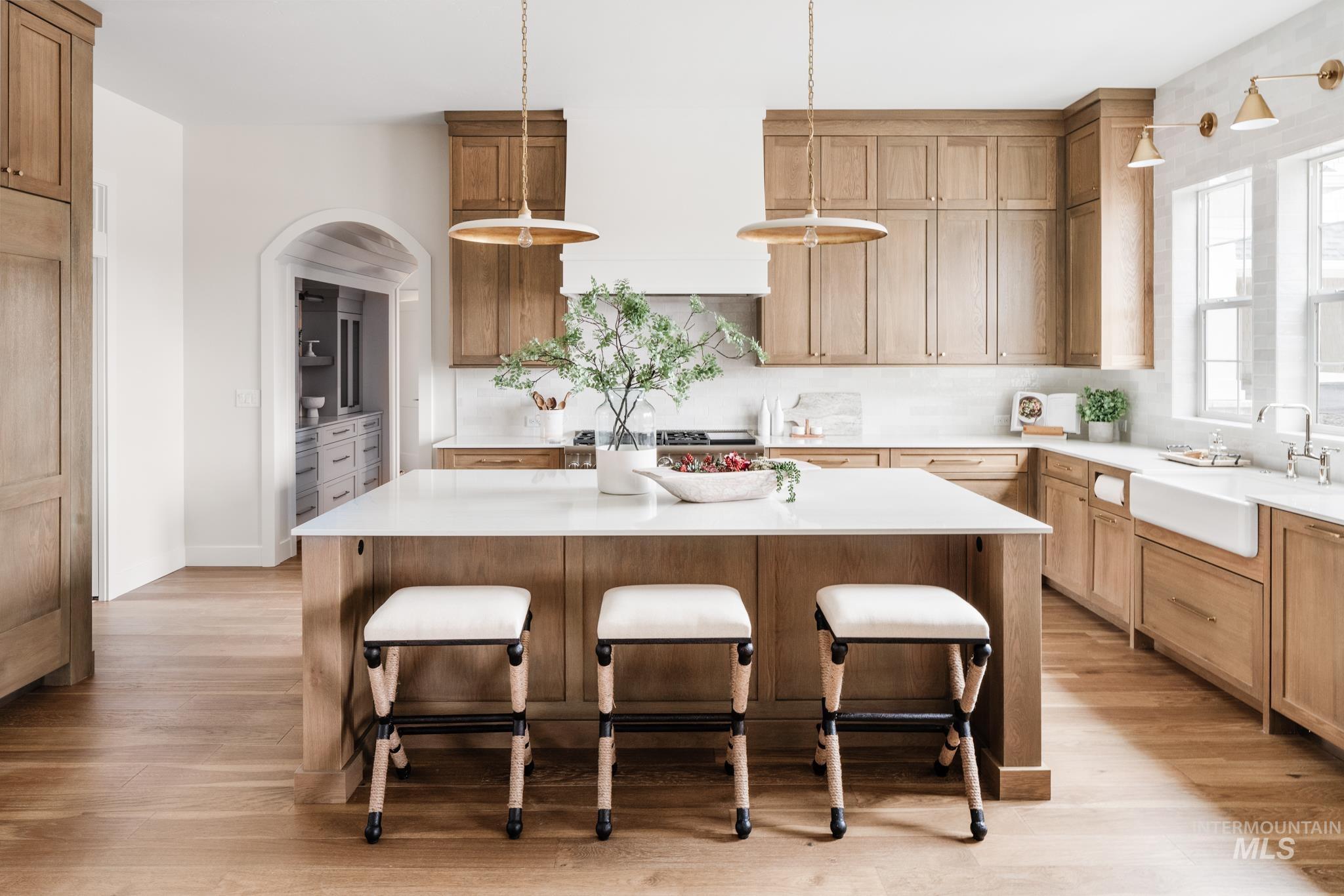 Kitchen with a kitchen bar, hanging light fixtures, light wood finished floors, and decorative backsplash
