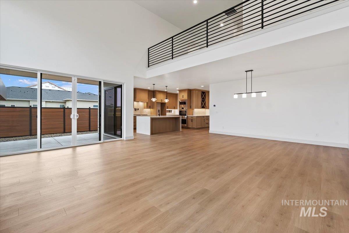 Unfurnished living room with a towering ceiling, light wood-style flooring, and recessed lighting