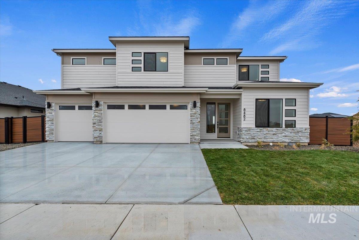 Prairie-style house with stone siding, an attached garage, and concrete driveway
