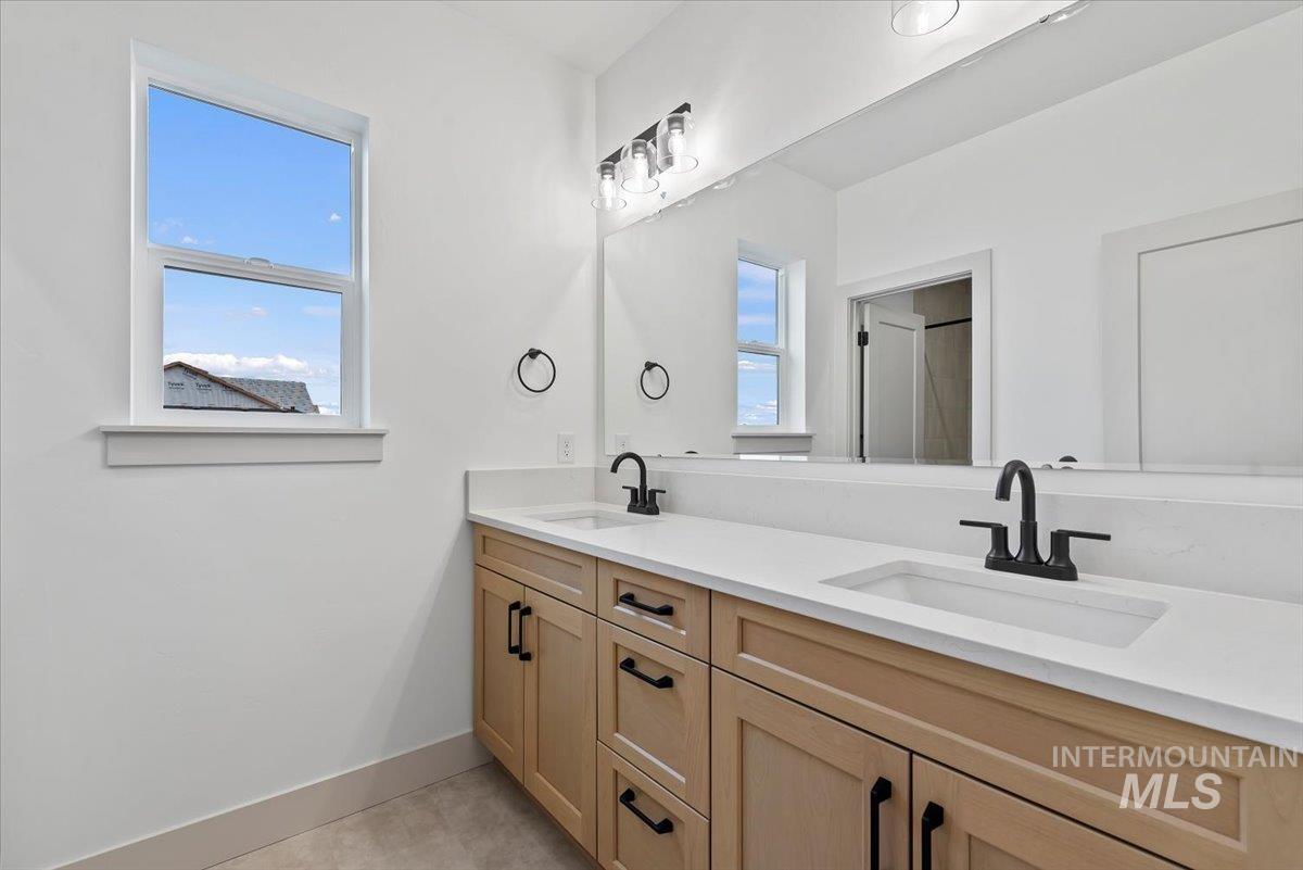 Full bathroom with double vanity and baseboards