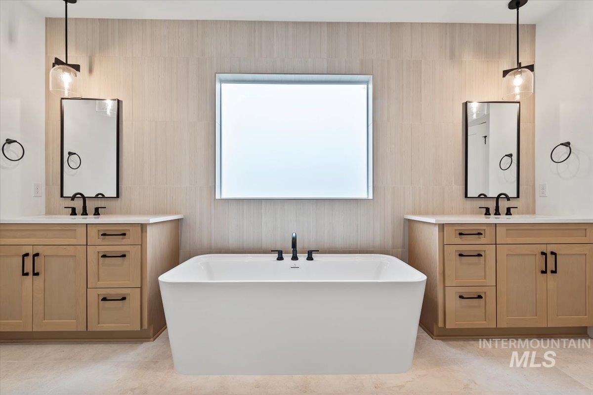 Bathroom featuring two vanities and a soaking tub