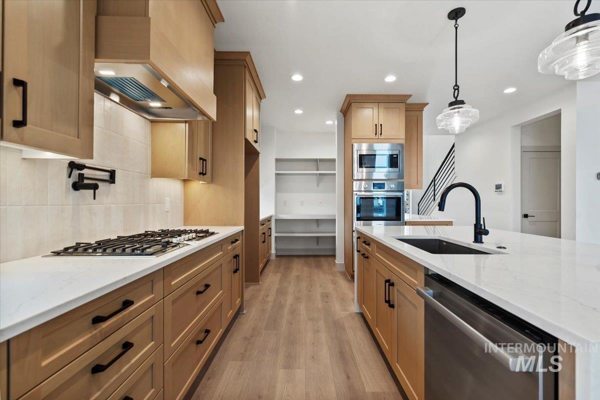 Kitchen featuring light stone counters, appliances with stainless steel finishes, recessed lighting, light wood-type flooring, and custom range hood