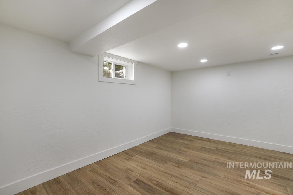 Below grade area with light wood-type flooring and recessed lighting