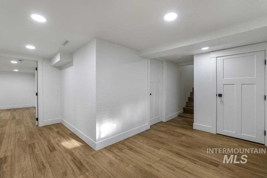Finished basement with stairs, light wood finished floors, and recessed lighting