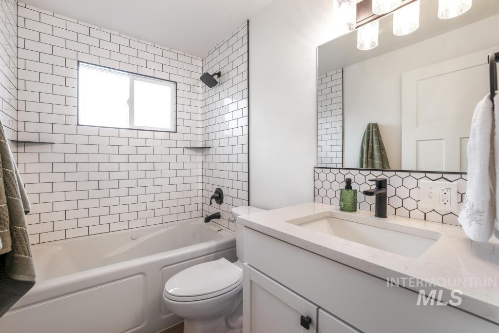 Full bath featuring shower / bathtub combination, vanity, and decorative backsplash